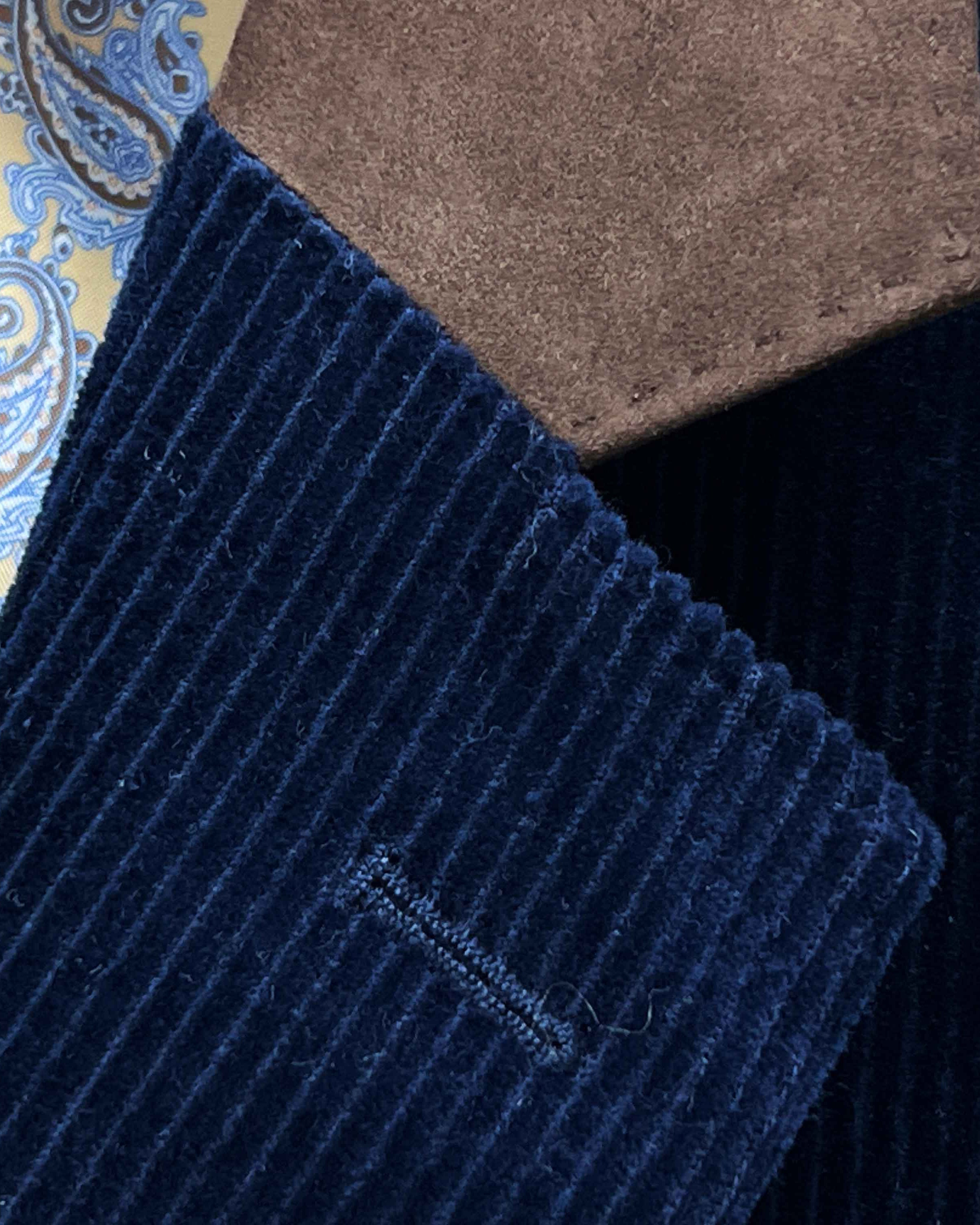 Classic notch lapel detail on deep navy blue corduroy sport coat showing hand pick stitching and brown suede collar