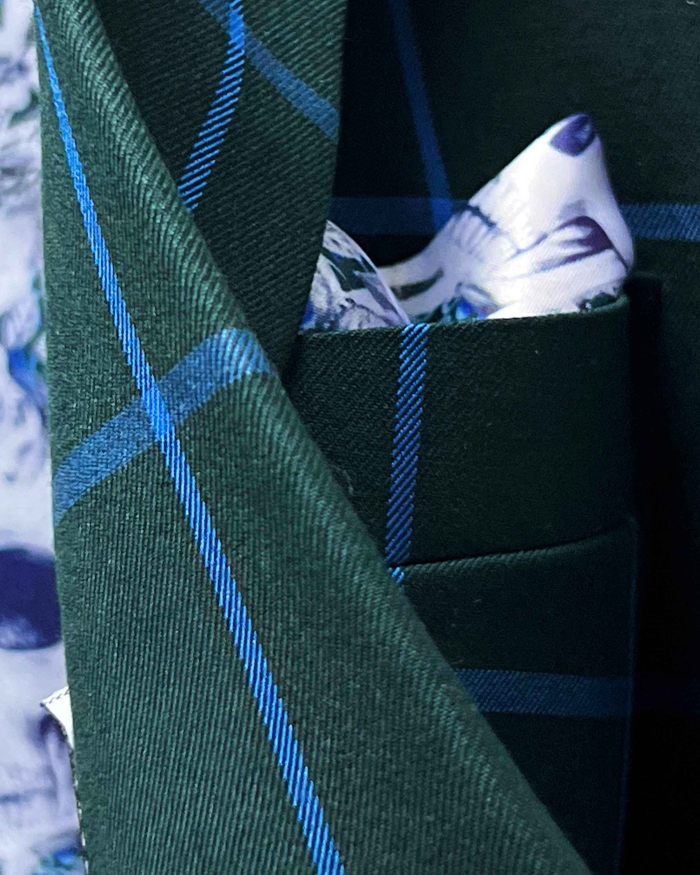 Close-up of Super 130s Australian merino wool fabric showing forest green base with bright blue windowpane check pattern