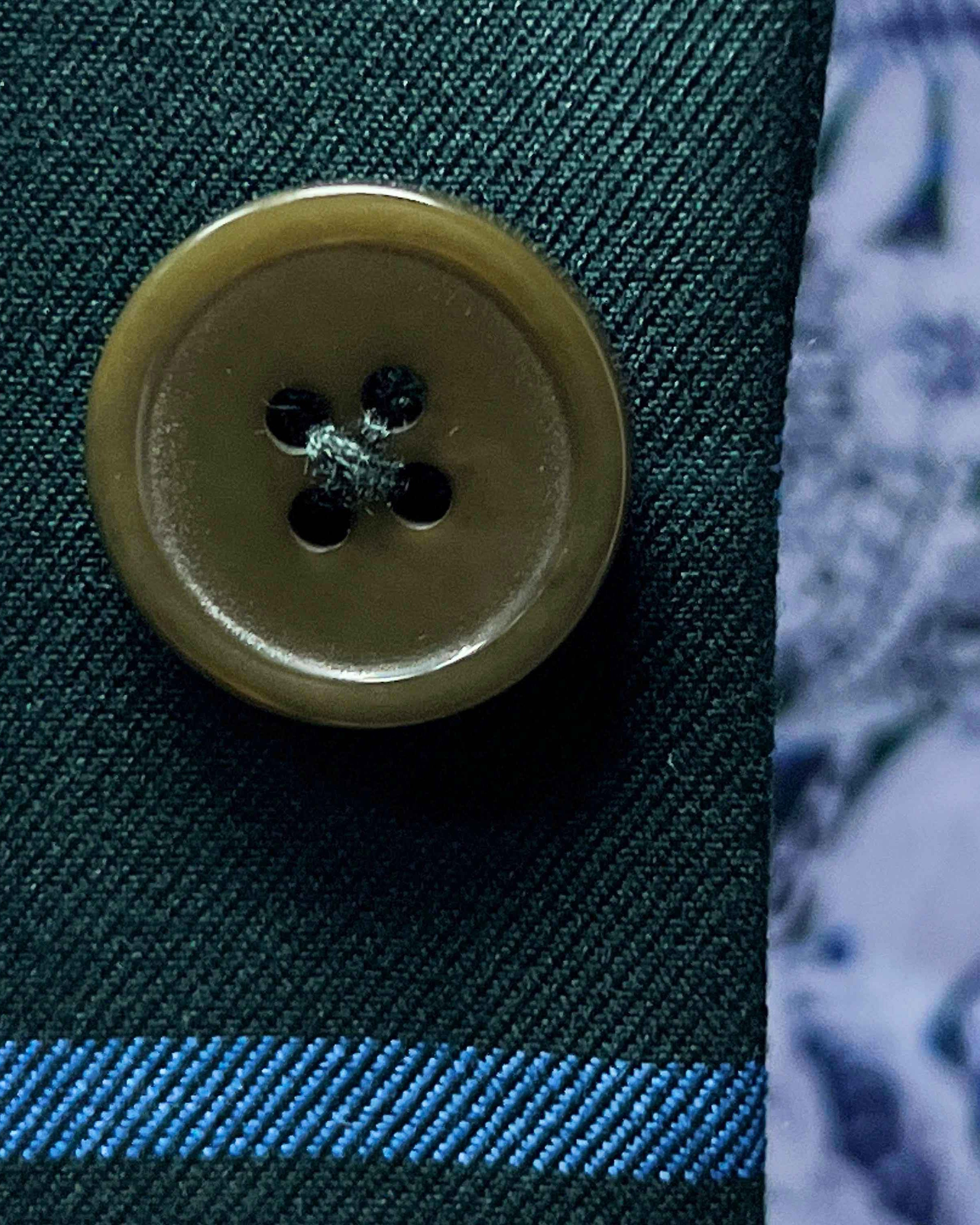 Close-up of green tortoise shell buttons on forest green windowpane sport coat showing natural patterns