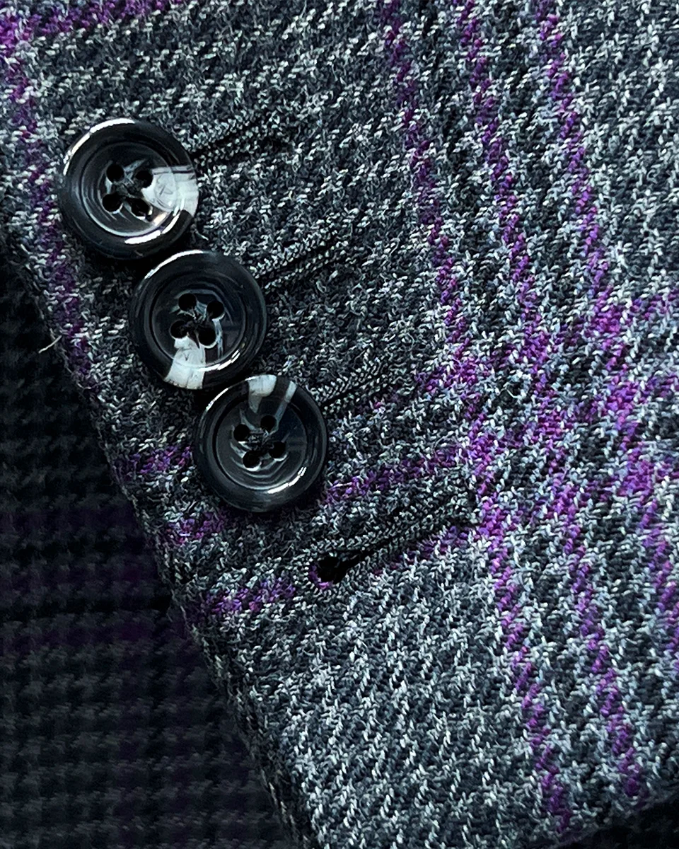 Detail shot of functional buttonholes on sleeve cuff of grey and purple plaid sport coat