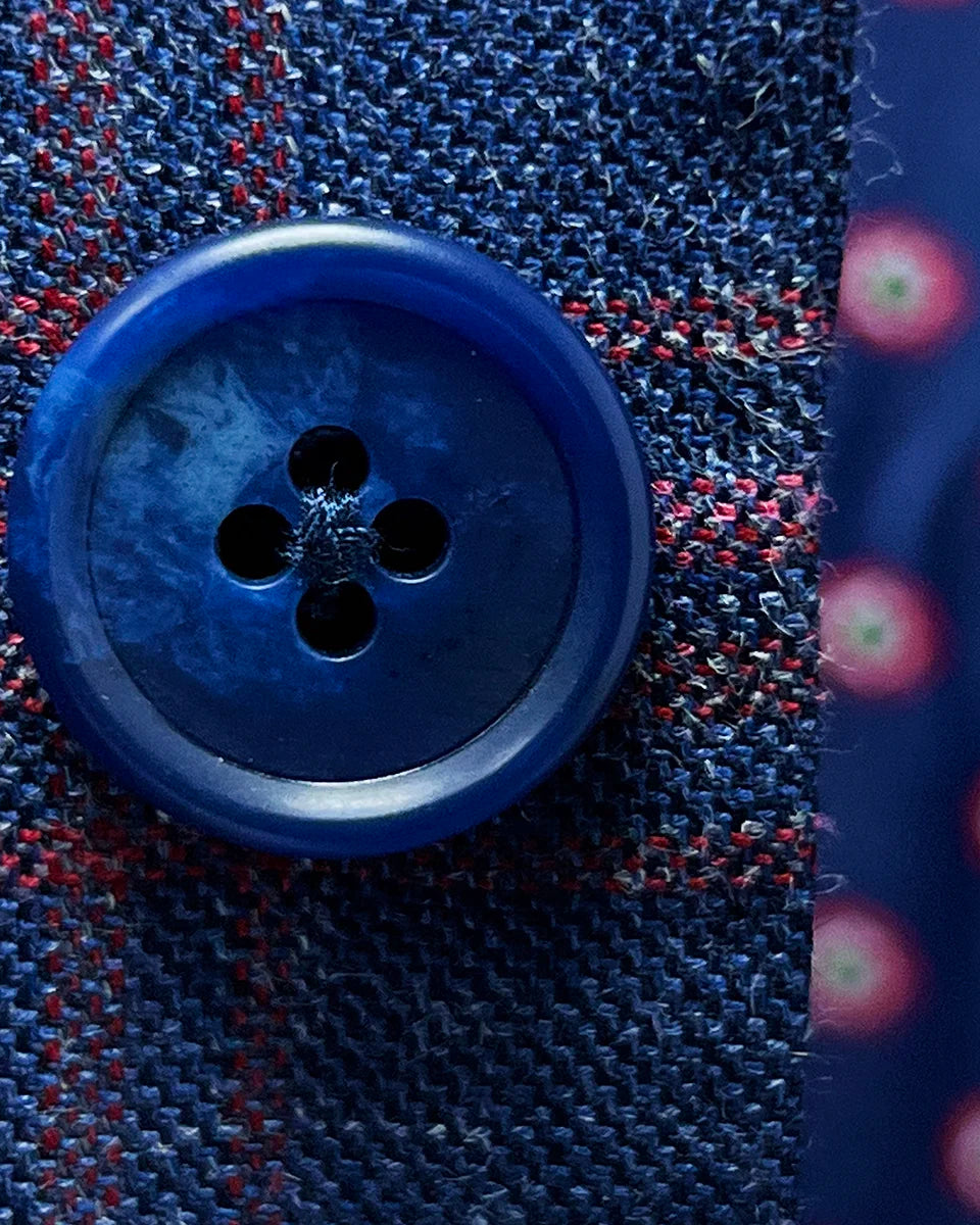 Close-up of navy horn buttons showing natural marbled texture and quality construction against the indigo blue windowpane fabric