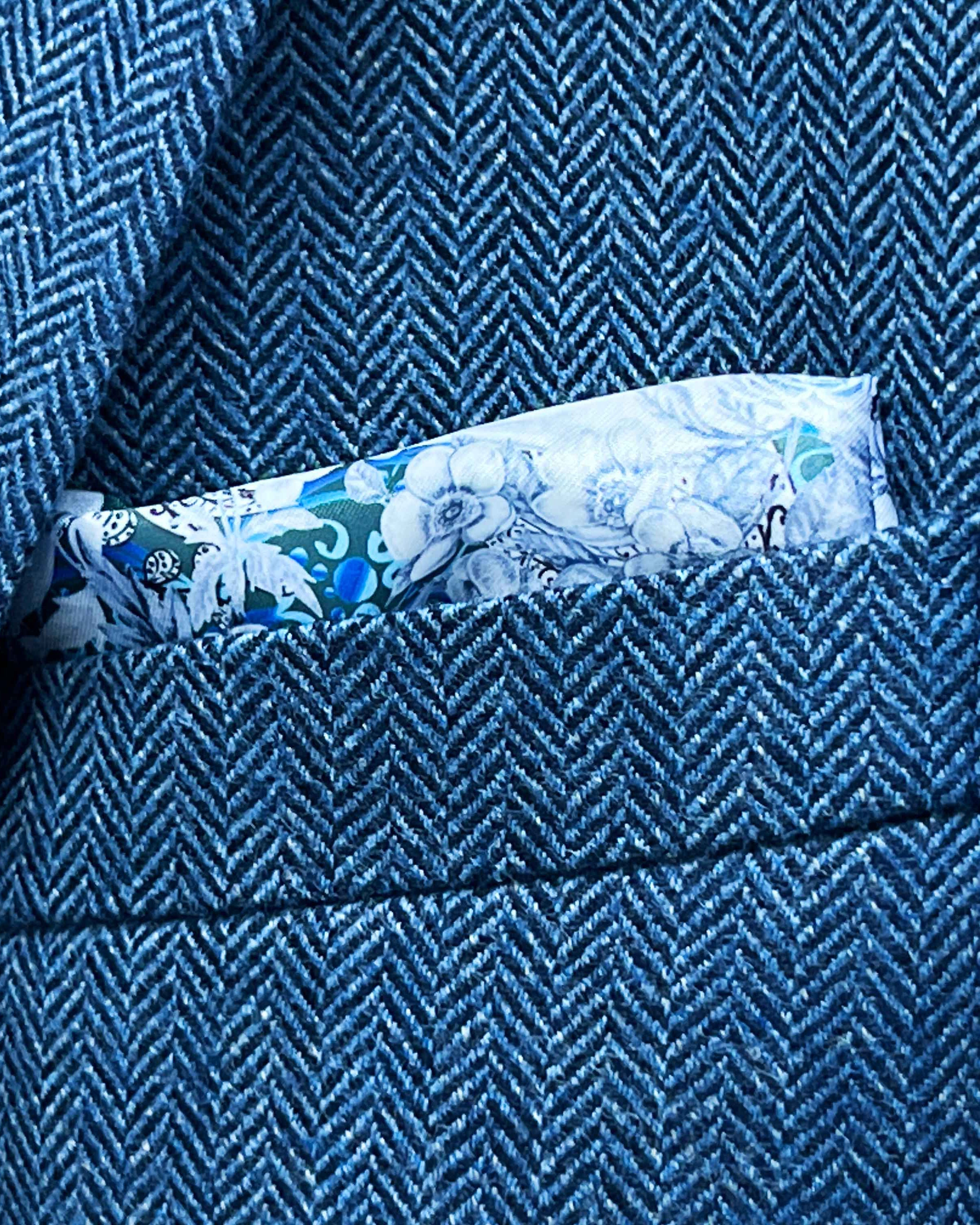 Breast pocket of indigo blue herringbone tweed sport coat with built-in floral skull pocket square and hand-finished edges