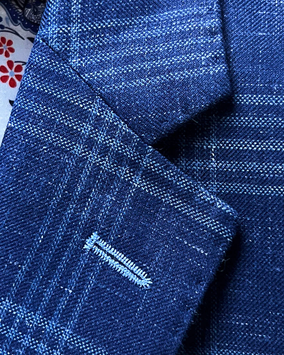 Classic notch lapel construction with pick stitching details and white contrast buttonhole on indigo windowpane linen-wool blend