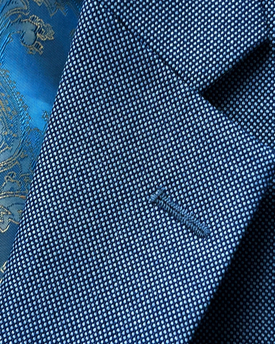 Detail of light blue birdseye suit jacket focusing on the classic notch lapel