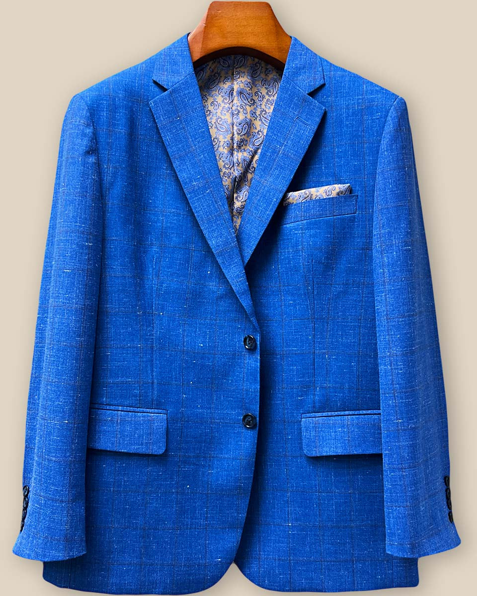 Front button stance detail highlighting navy horn buttons against light blue windowpane fabric with brown pattern overlay