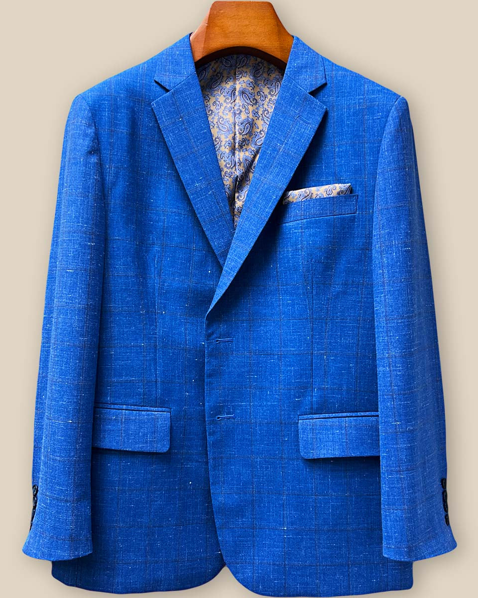 Close-up detail of chocolate brown contrast buttonholes on light blue windowpane sport coat sleeve, showcasing precision hand-stitched craftsmanship