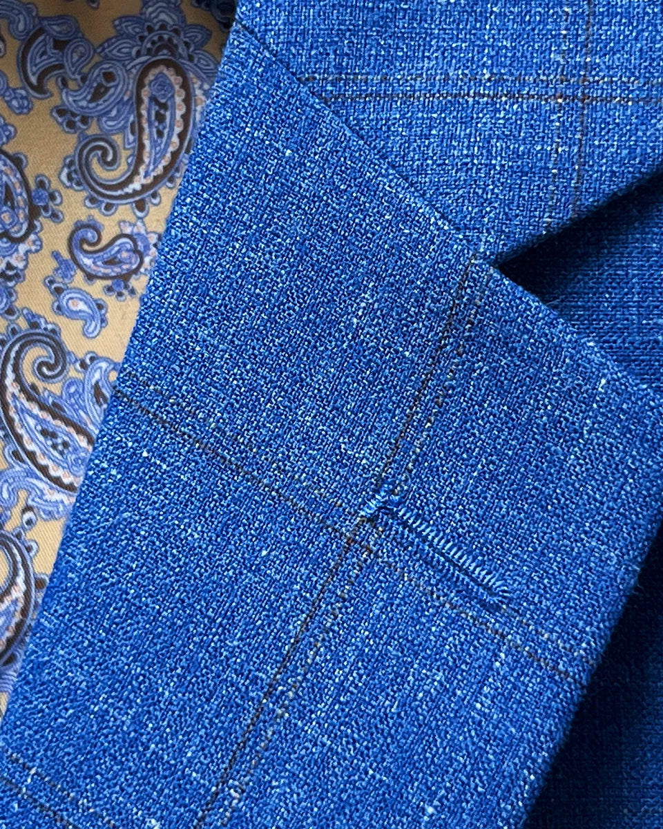 Classic notch lapel construction displaying proper proportions and clean tailoring lines on light blue windowpane jacket