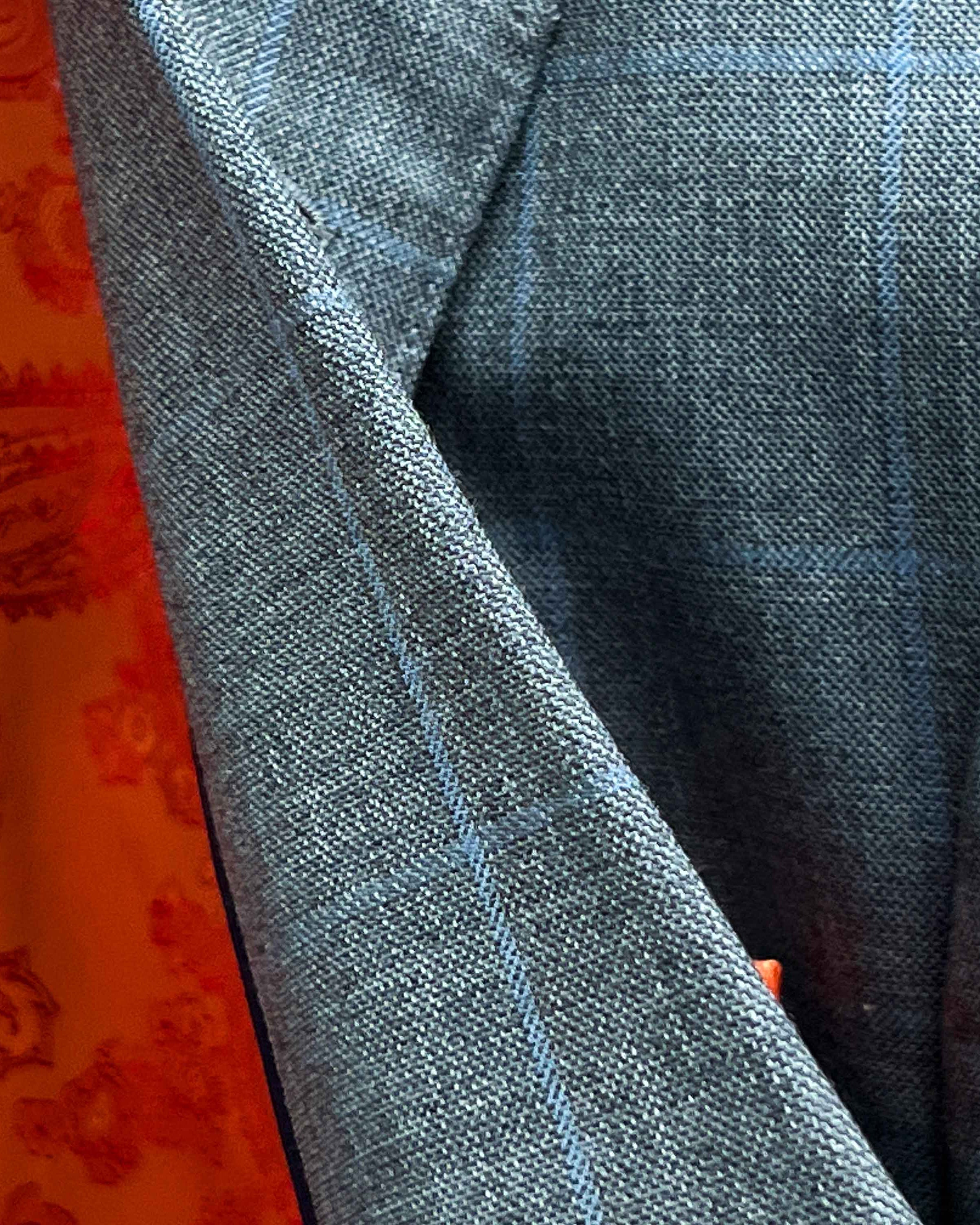 Detailed fabric texture view of Super 130's merino wool showing light gray base with light blue windowpane pattern