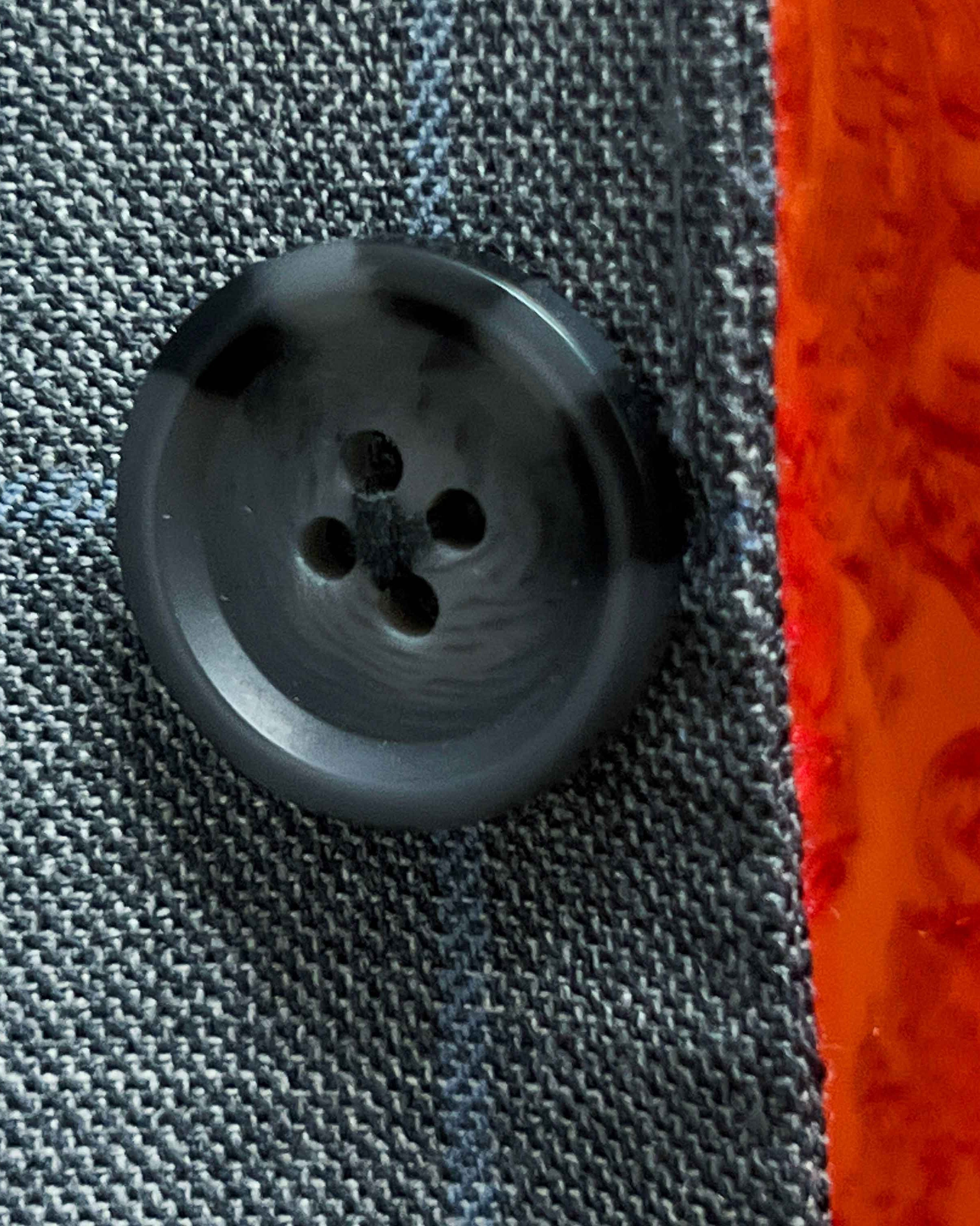 Close-up of dark gray horn buttons on light gray with light blue windowpane sport coat showing natural marble-like patterns