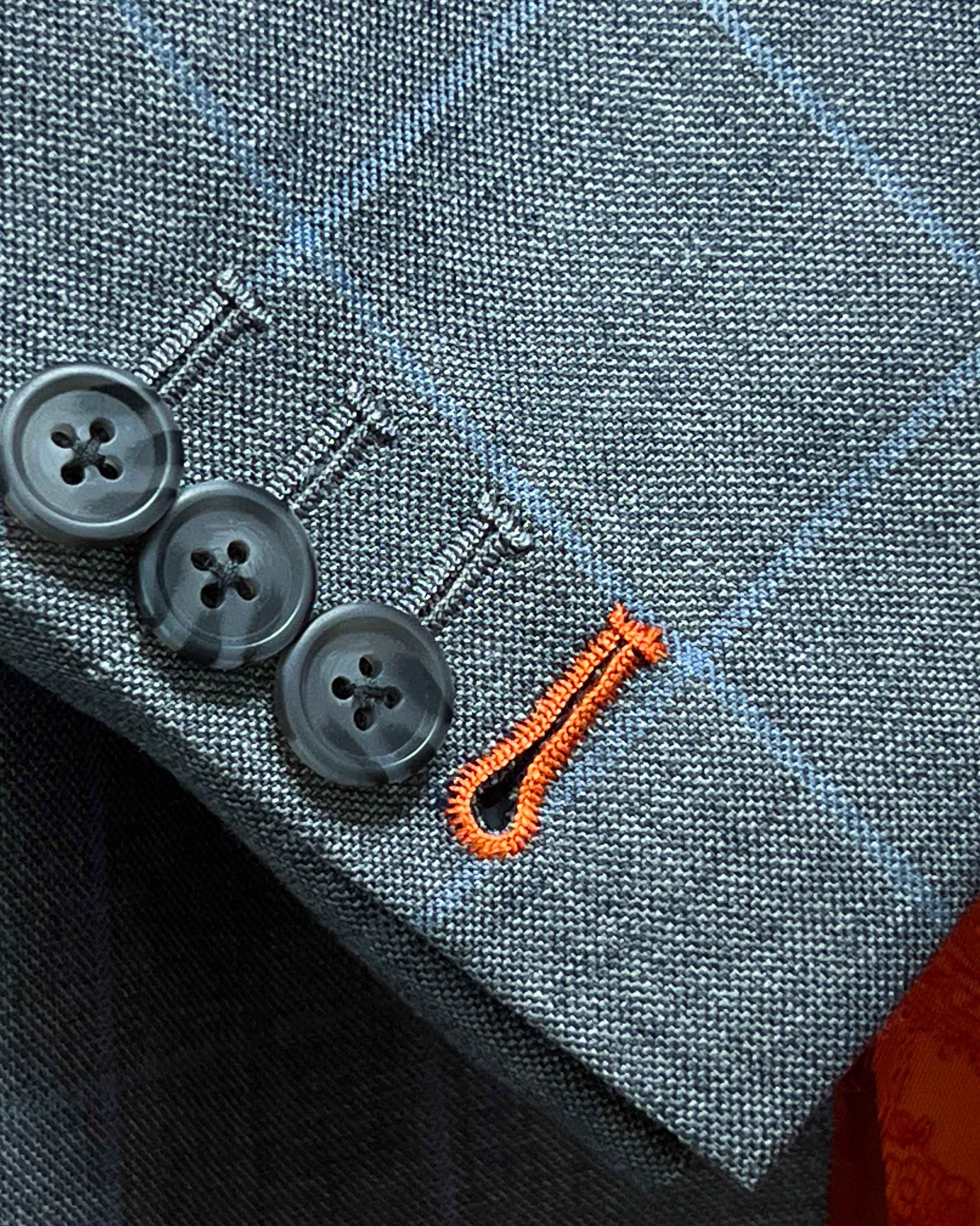 Contrast bright orange accent buttonholes on light gray with light blue windowpane sport coat sleeve showing precise hand-finished stitching