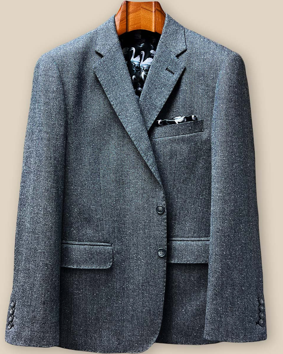 Detail shot of light grey horn marble buttons against salt & pepper tweed fabric with pick stitching