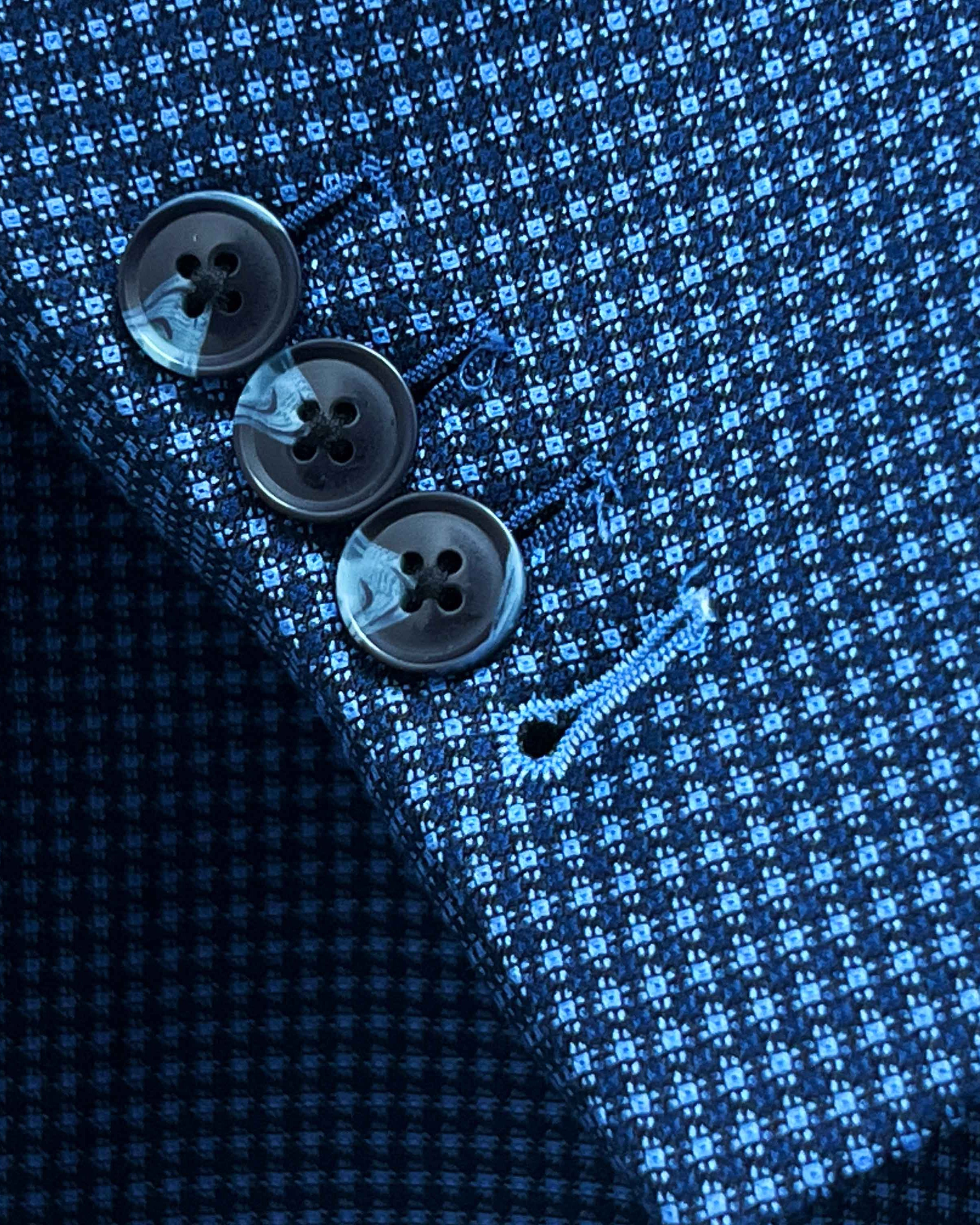 Sport coat sleeve cuff showing functional buttonholes with contrast light blue accent stitching on medium blue micro check fabric