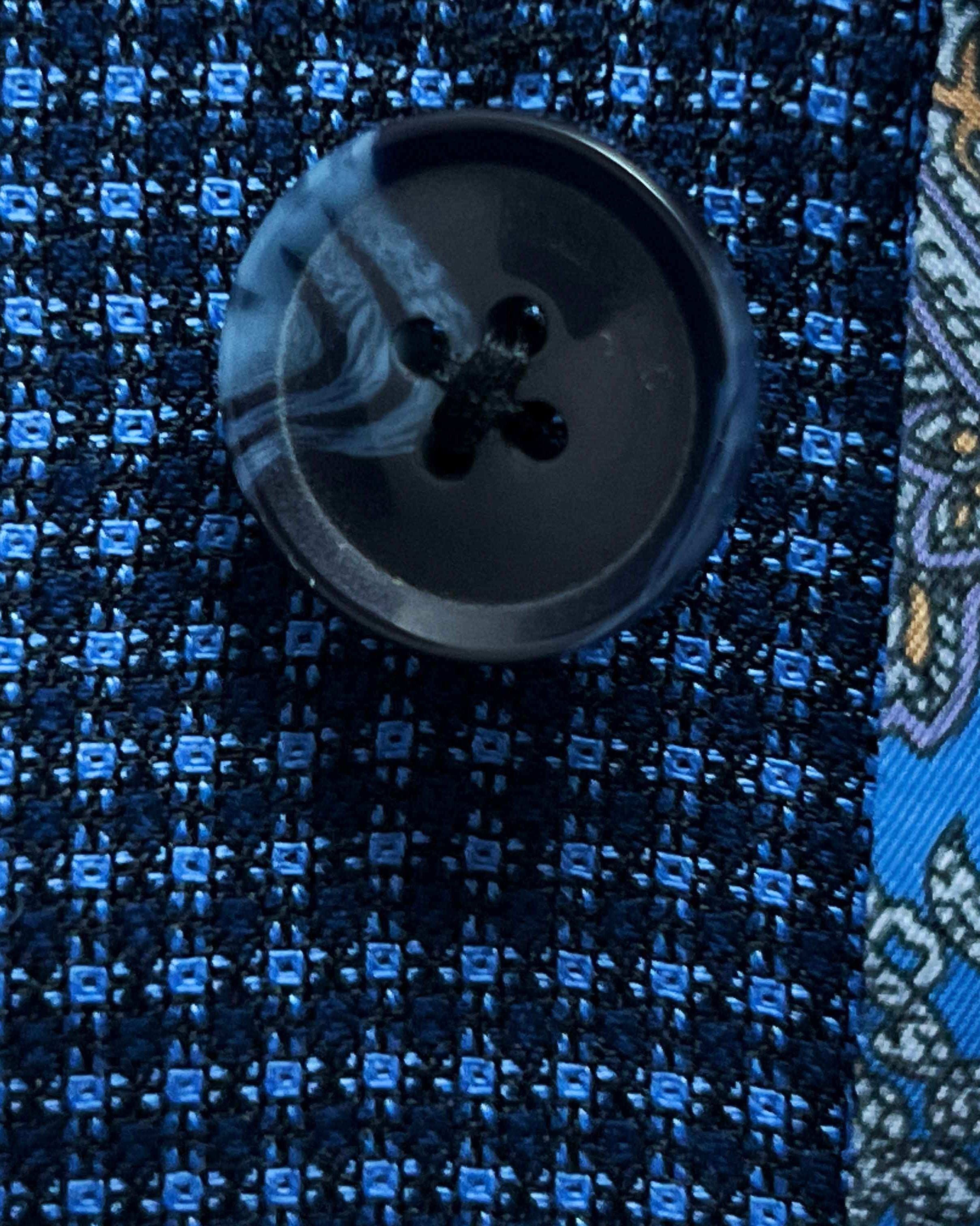 Close-up of navy marbled horn buttons on medium blue micro check sport coat showing natural patterns