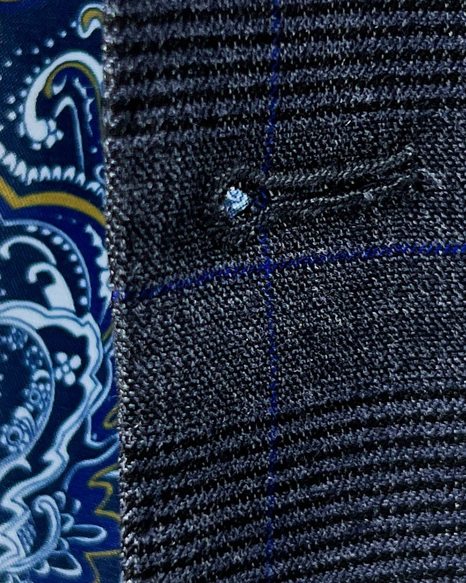 Extreme close-up of the precision hand-stitching around a buttonhole, highlighting the care and attention to detail in this made to measure suit