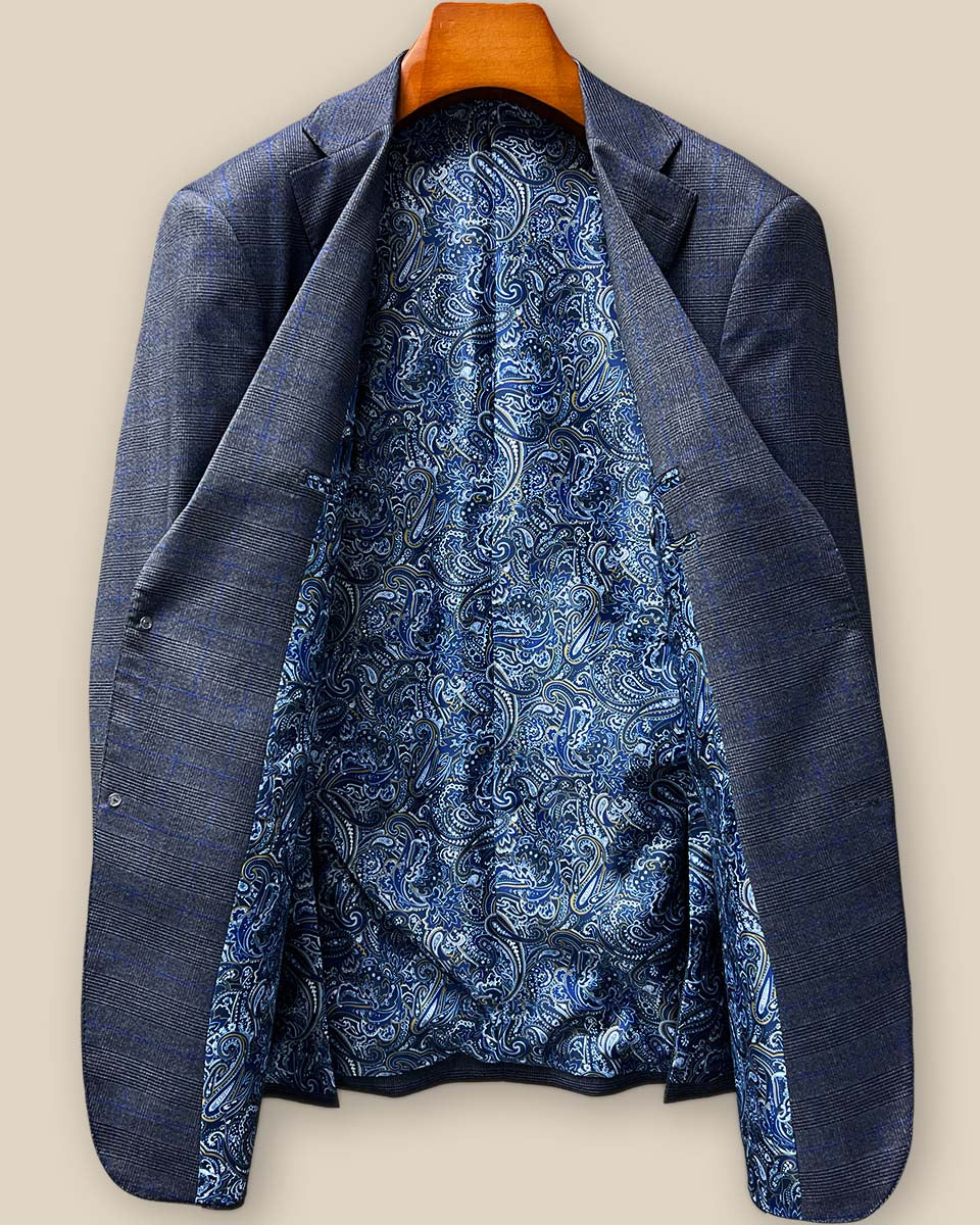 Full spread view of the bespoke suit jacket's striking blue paisley lining with gold and white accents, showcasing the hidden luxury that elevates this tailored garment