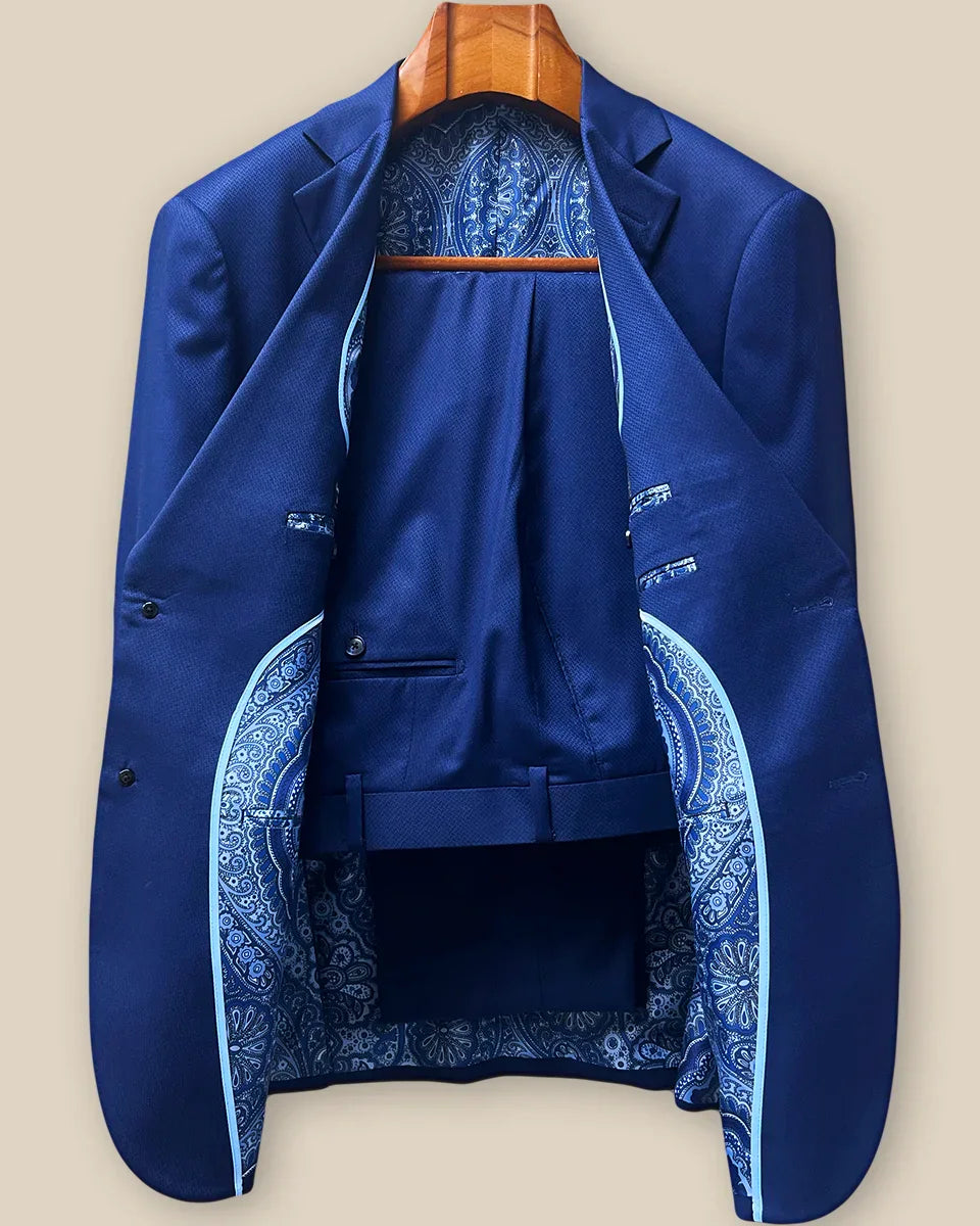 Complete two-piece navy blue geometric textured custom suit displayed on hanger showing jacket and trousers