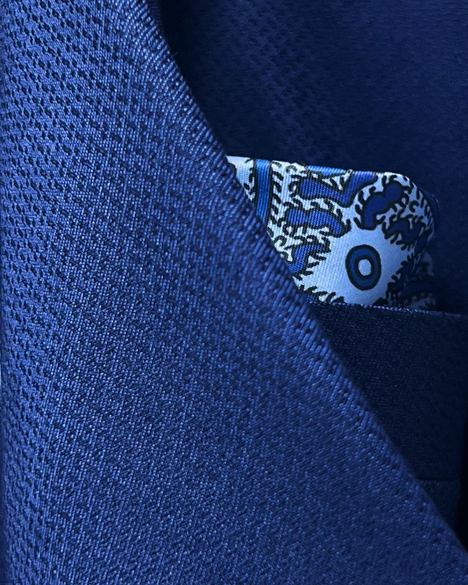 Close-up detail of geometric textured pattern on navy blue suit fabric showing intricate weave structure