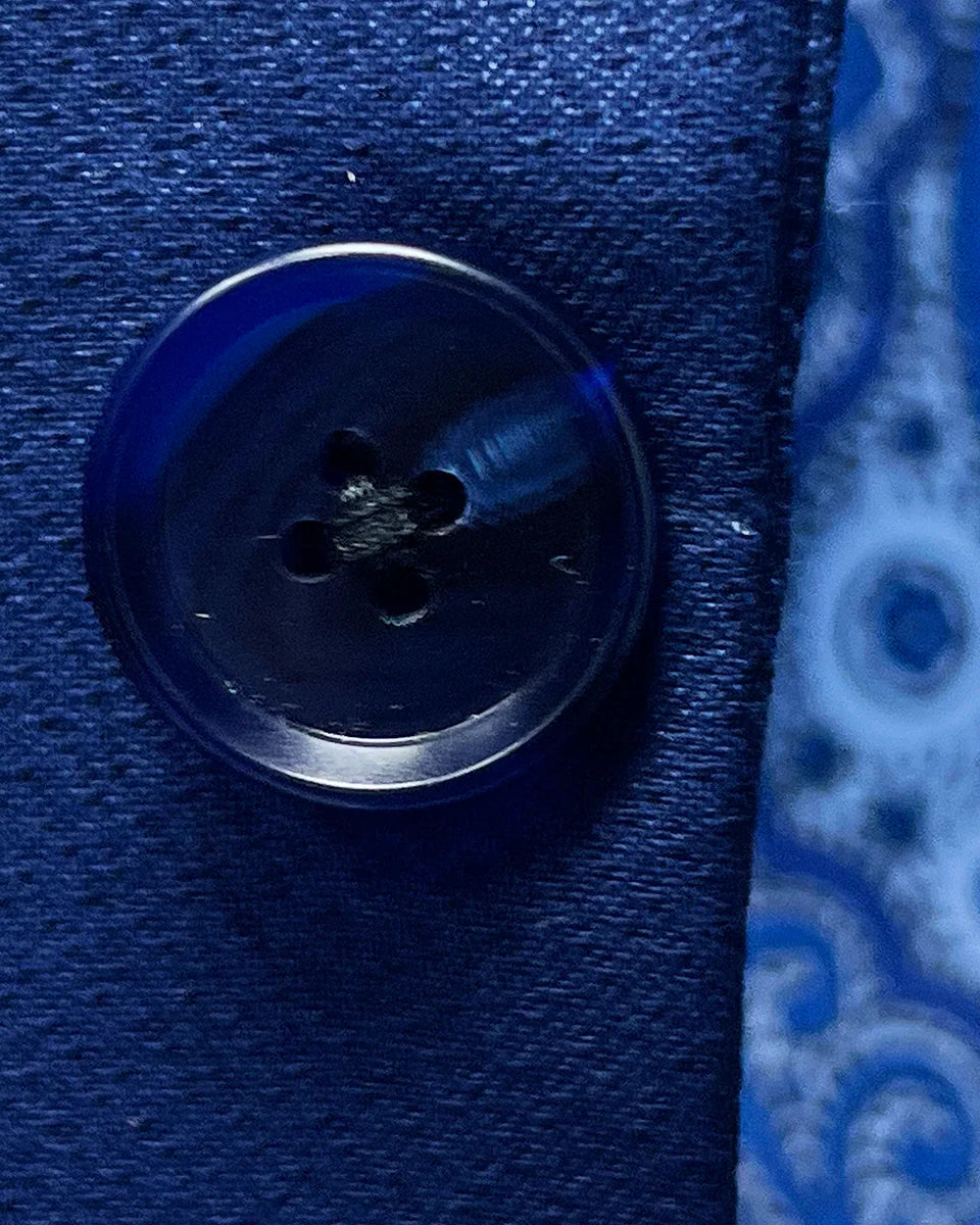 Close-up of navy blue horn buttons on geometric textured suit jacket showing natural marble-like patterns