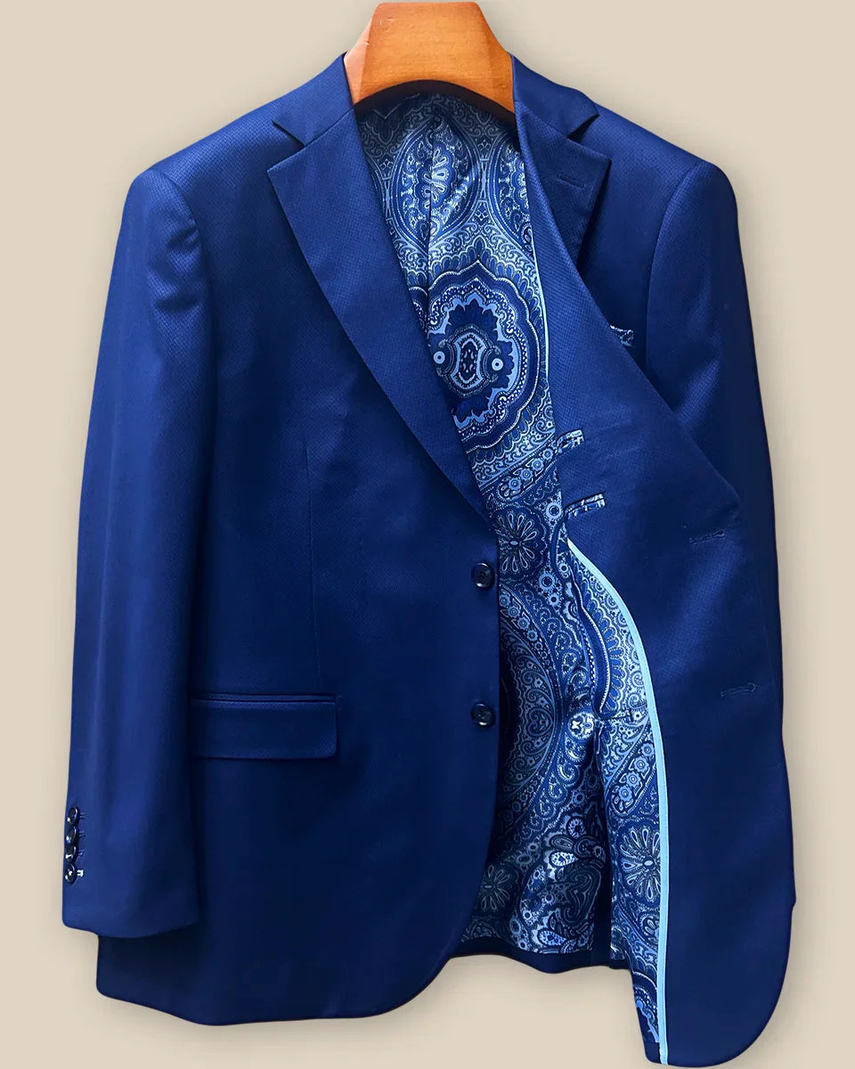 Interior left side of navy blue geometric textured suit jacket displaying rich blue intricate paisley lining with inner pocket