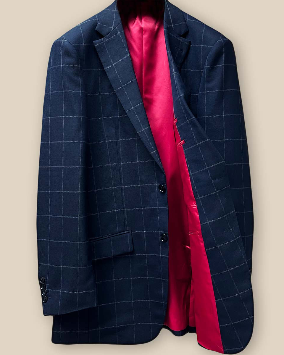 Interior view of navy windowpane suit jacket, displaying tomato red silk bemberg lining and left chest pocket