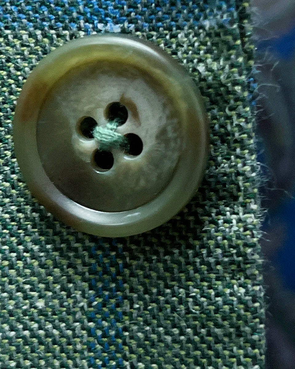 Detailed view of olive green horn buttons showcasing natural marble patterns and expert shank attachment