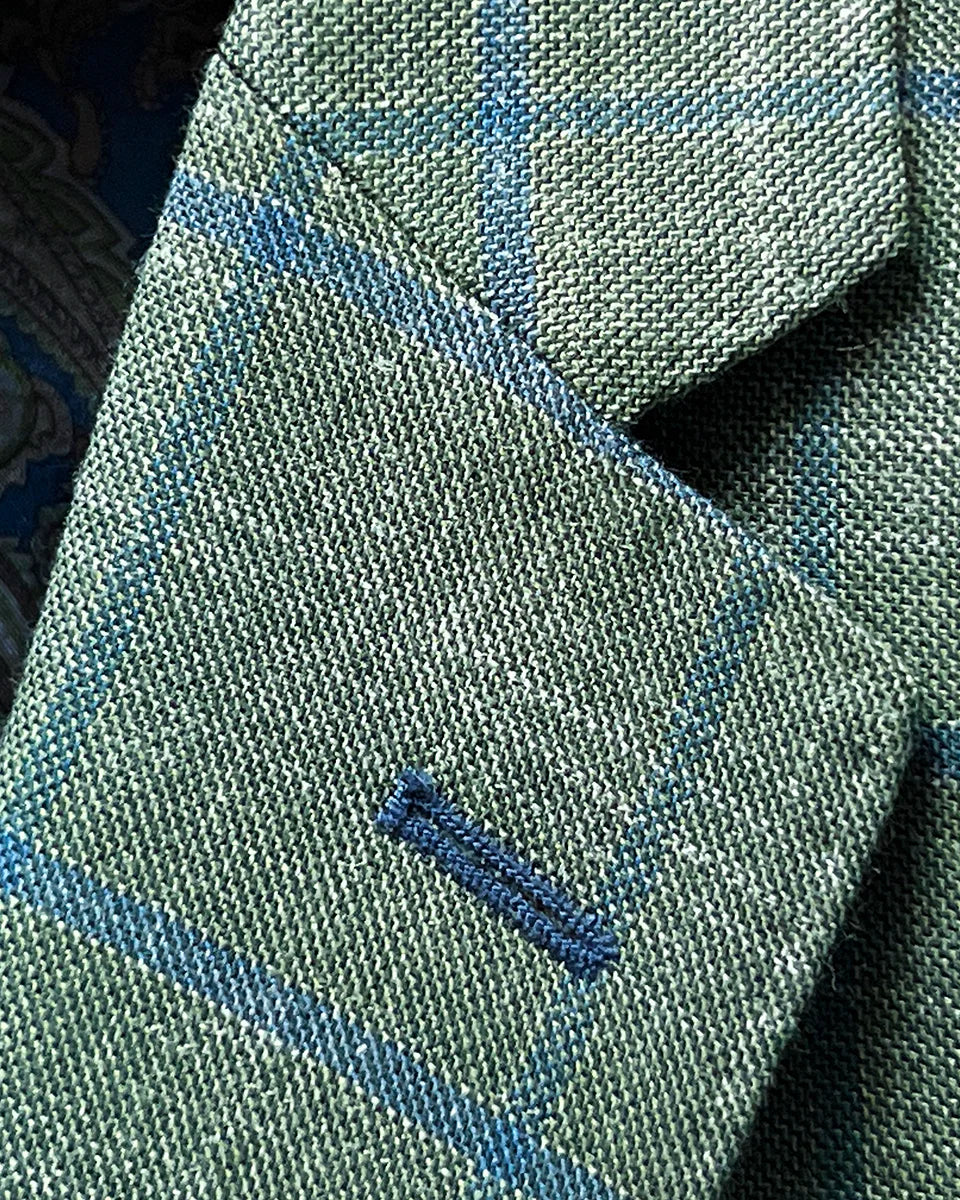 Classic notch lapel construction in olive green windowpane fabric with royal blue contrast buttonhole and expert canvas work