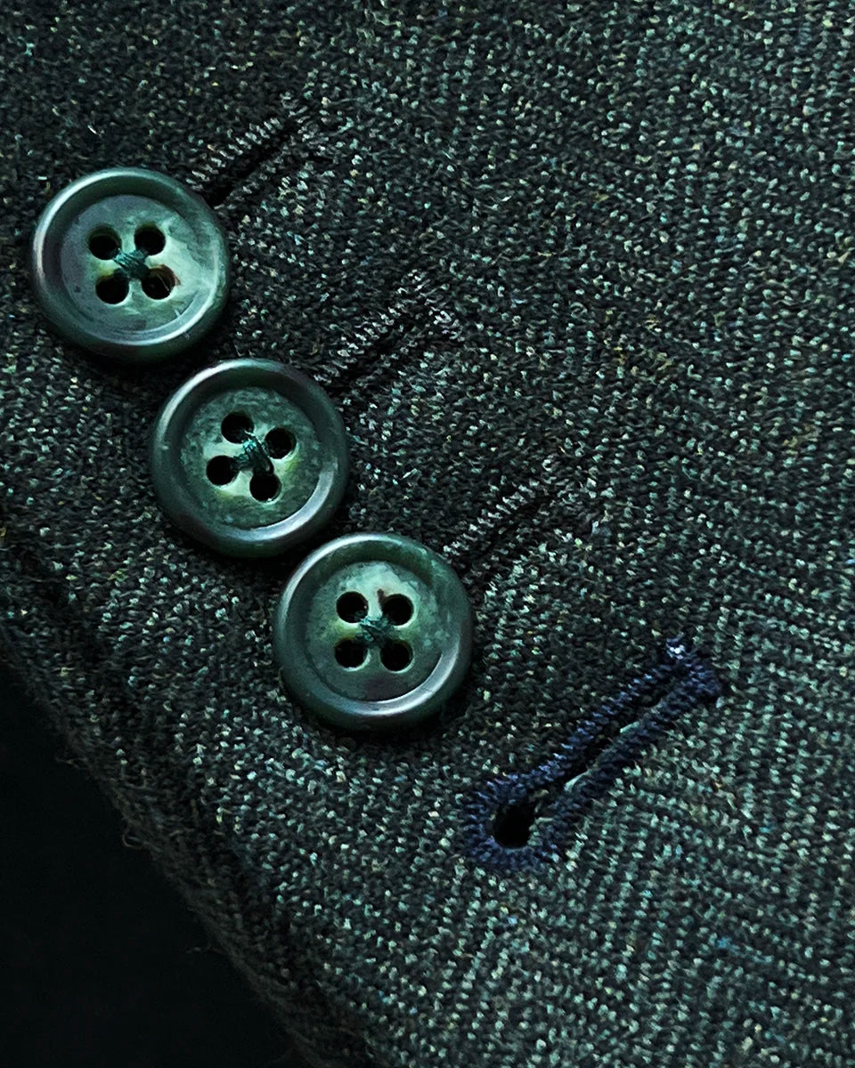 Working sleeve buttonholes with black contrast stitching on olive tweed sport coat featuring green horn buttons
