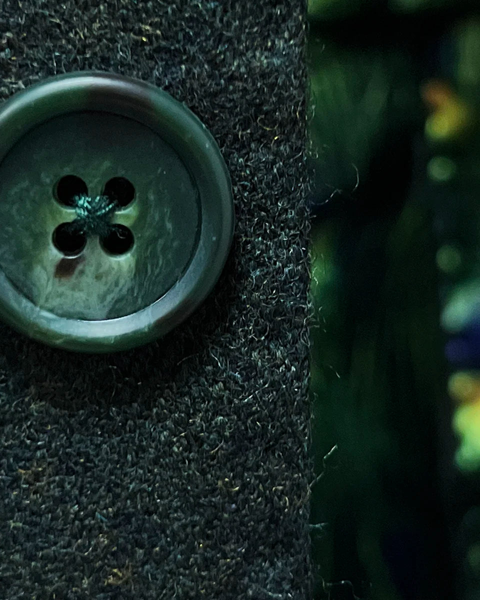 Green horn buttons with natural marbling detail complementing olive tweed fabric