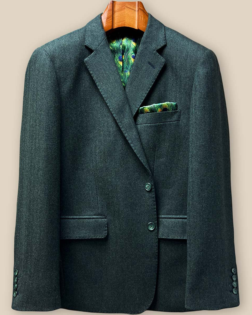 Close-up of green horn button closure system on olive herringbone tweed sport coat with pick stitching detail