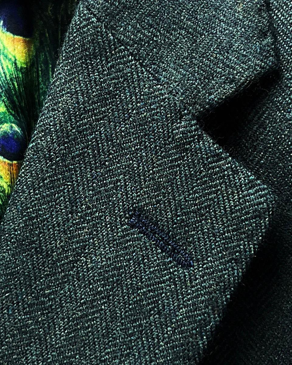 Classic notch lapel construction on olive green tweed sport coat with black contrast buttonhole and pick stitching