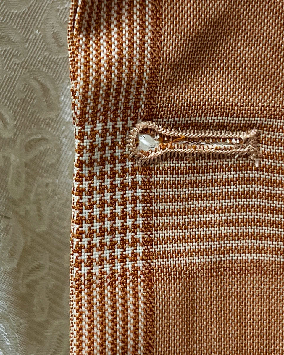 Macro view of buttonhole stitching on orange Prince of Wales glen plaid fabric