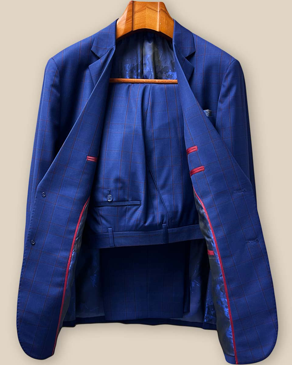 Complete two-piece custom suit display featuring royal blue Prince of Wales plaid pattern with crimson red accent details and classic tailored silhouette