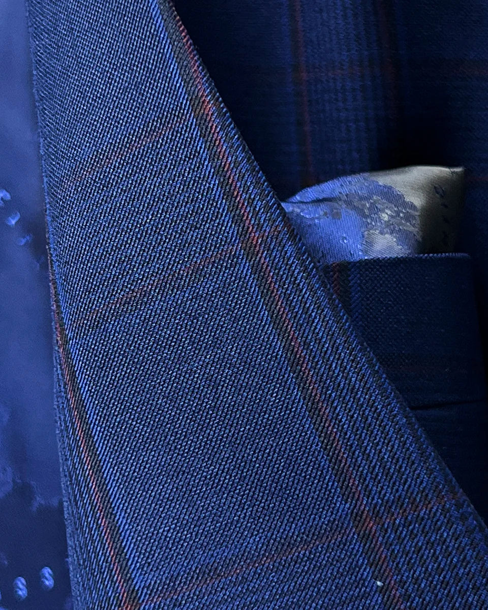 Lapel buttonhole detail with crimson red contrast stitching creating elegant accent against Prince of Wales plaid pattern