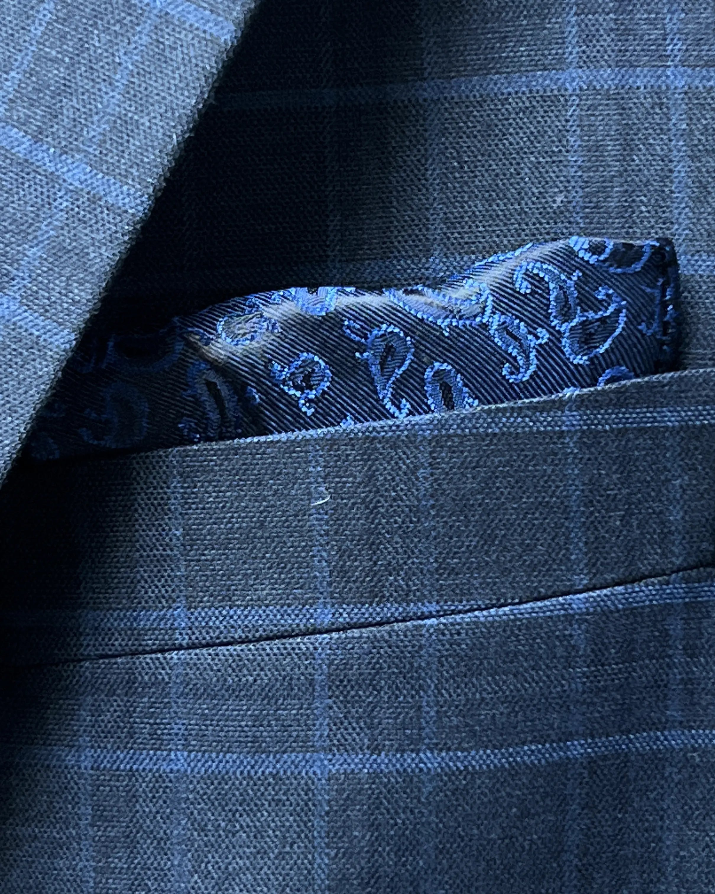 Breast pocket close up of slate blue windowpane check men's sport coat showing built in lining pocket square