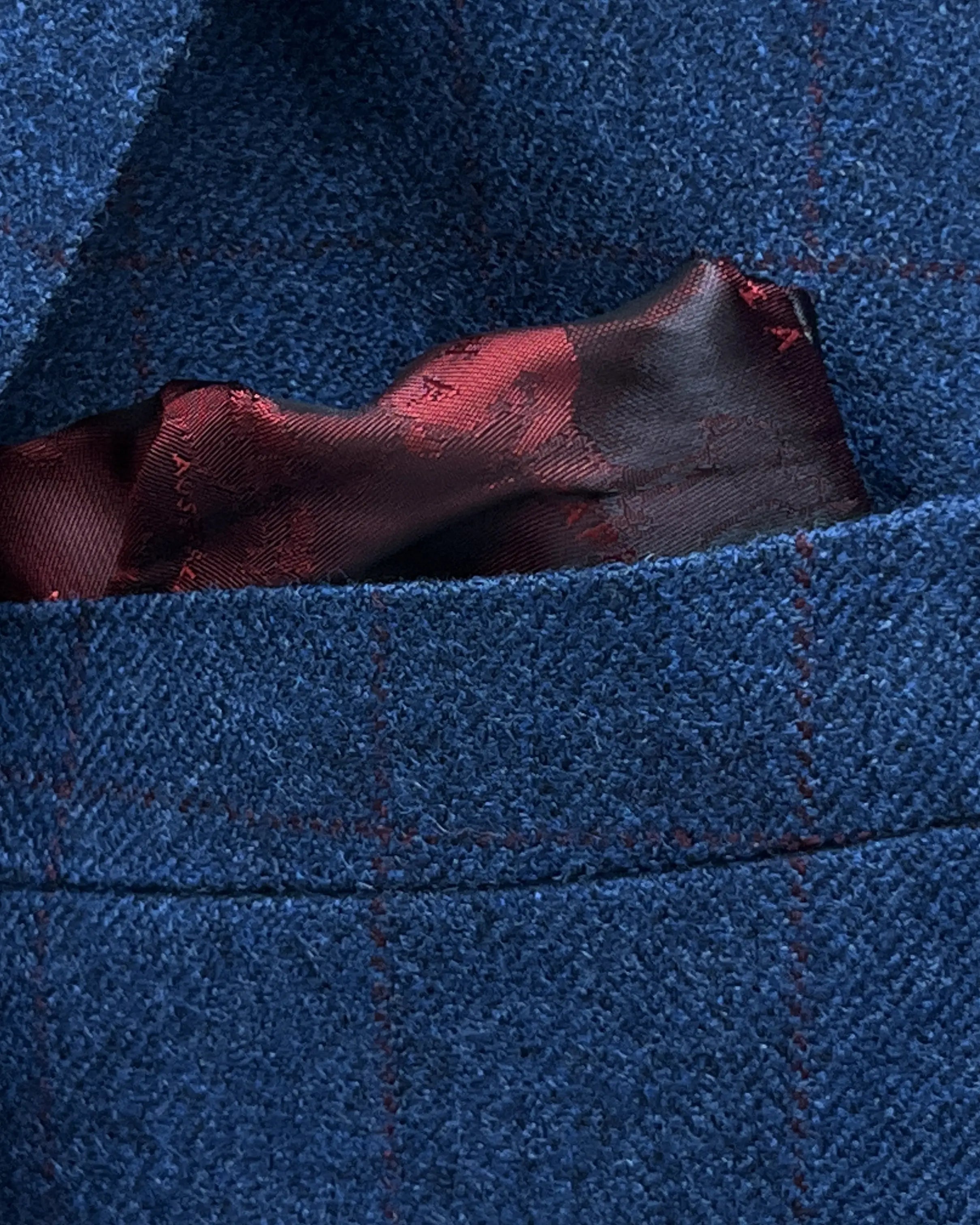 Breast pocket detail of teal blue with red windowpane men's sport coat showing the built in lining pocket square