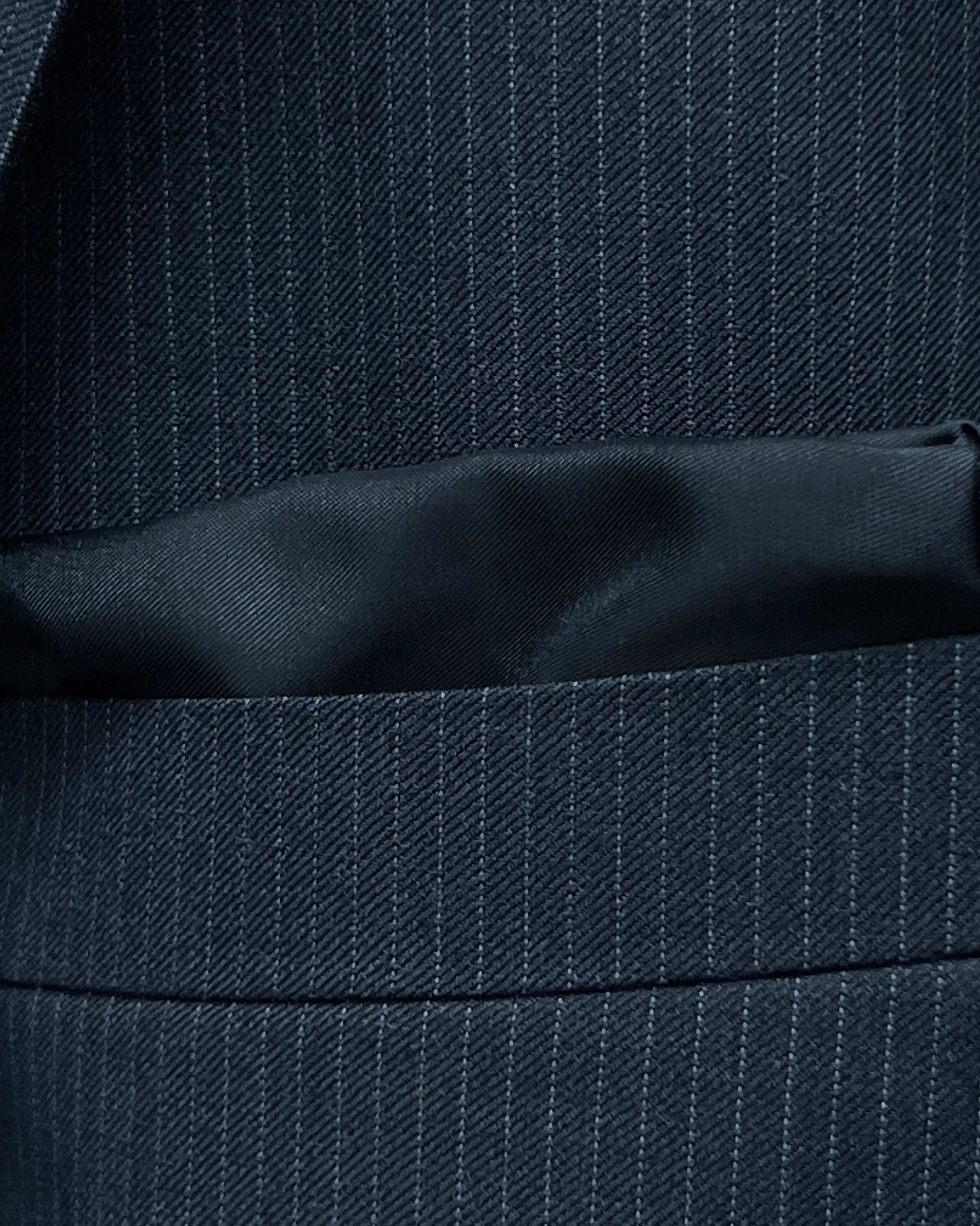 Breast pocket detail of black pinstripe men's suit showing the built in black silk cupro Bemberg pocket square