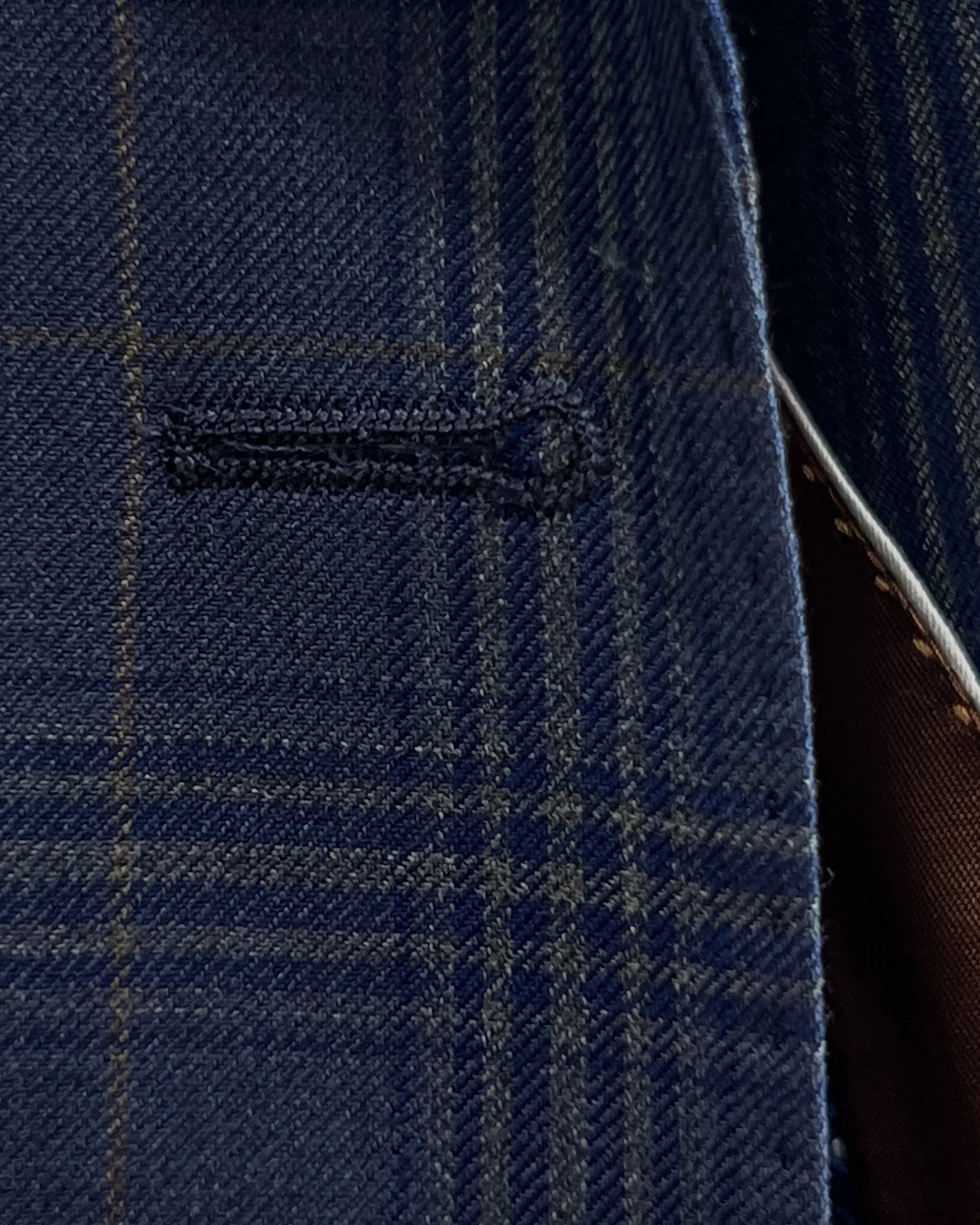 Buttonhole detail of blue windowpane plaid men's suit showing clean buttonhole stitching