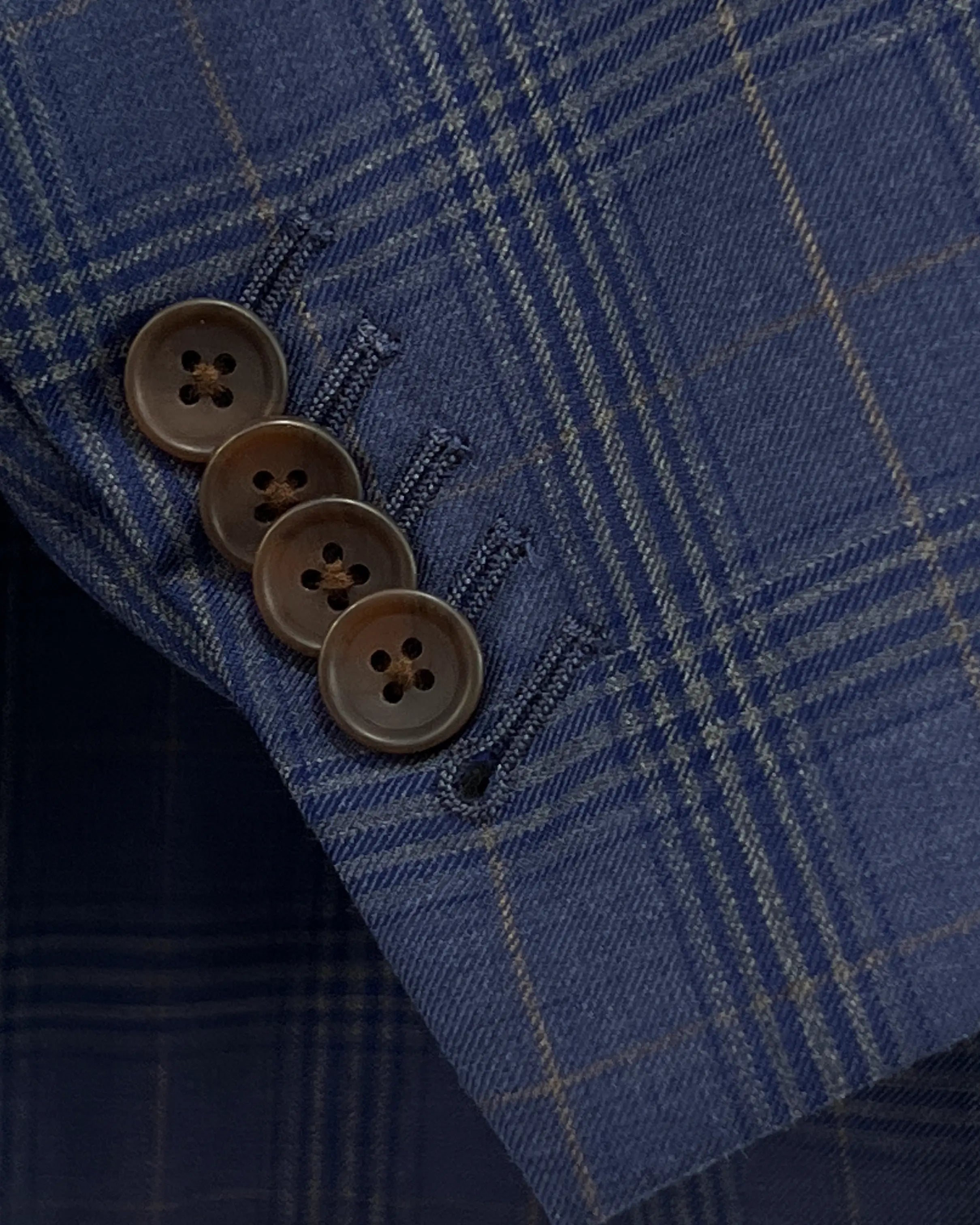 Sleeve cuff detail of blue windowpane plaid men's suit showing functional sleeve buttons