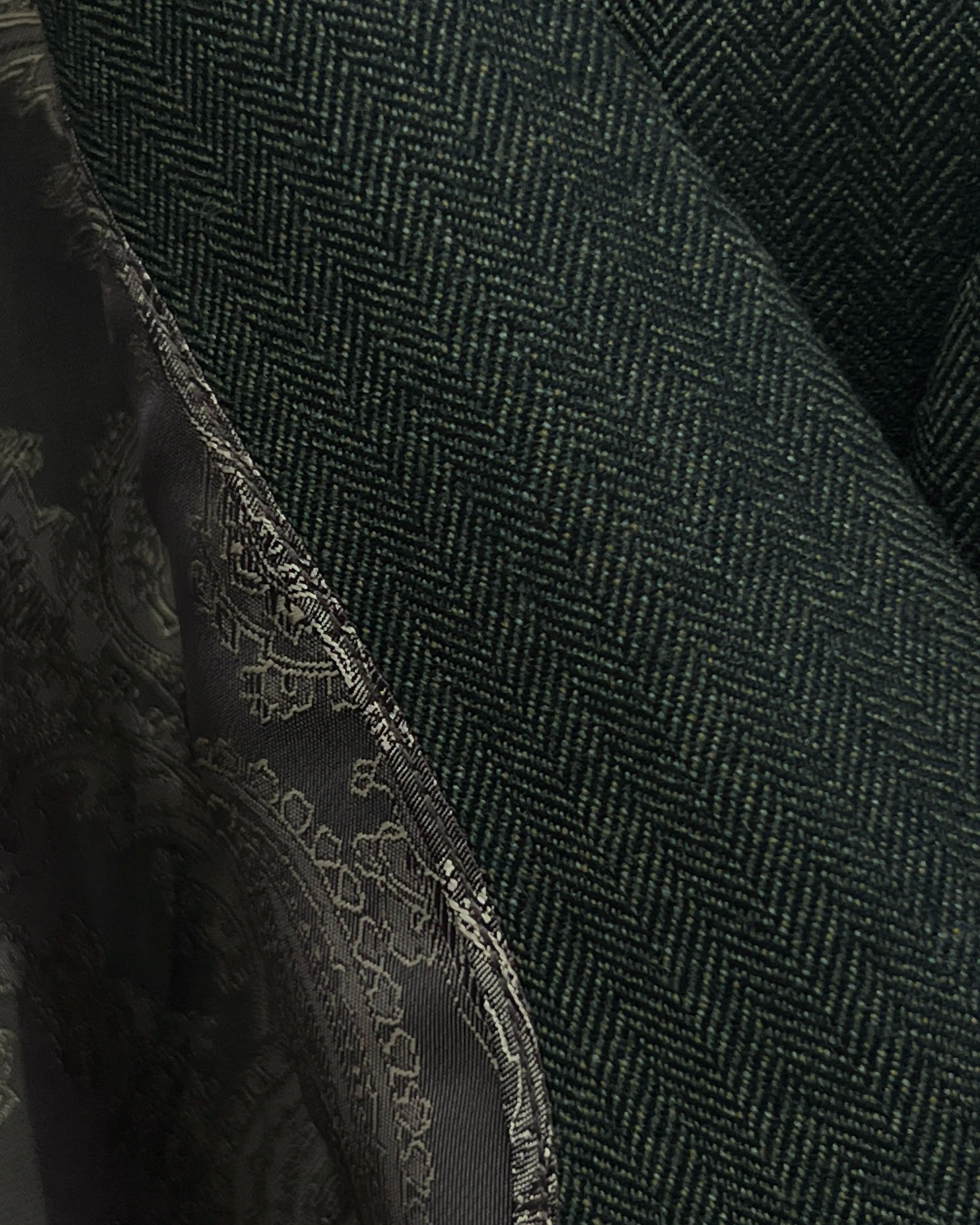 Fabric close up of dark forest green herringbone men's suit showing woven wool cloth texture