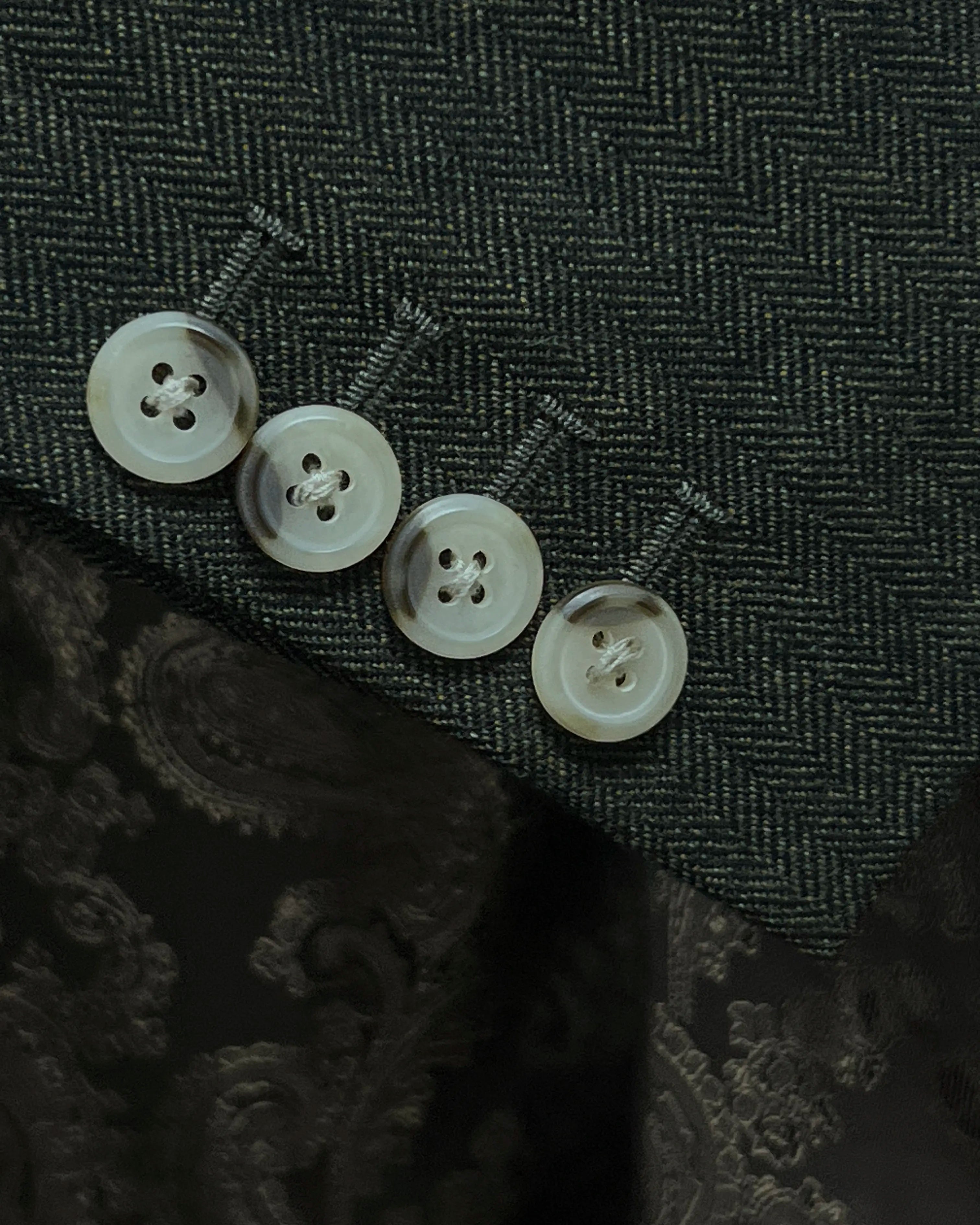 Sleeve close up of dark forest green herringbone men's suit showing functional sleeve buttons