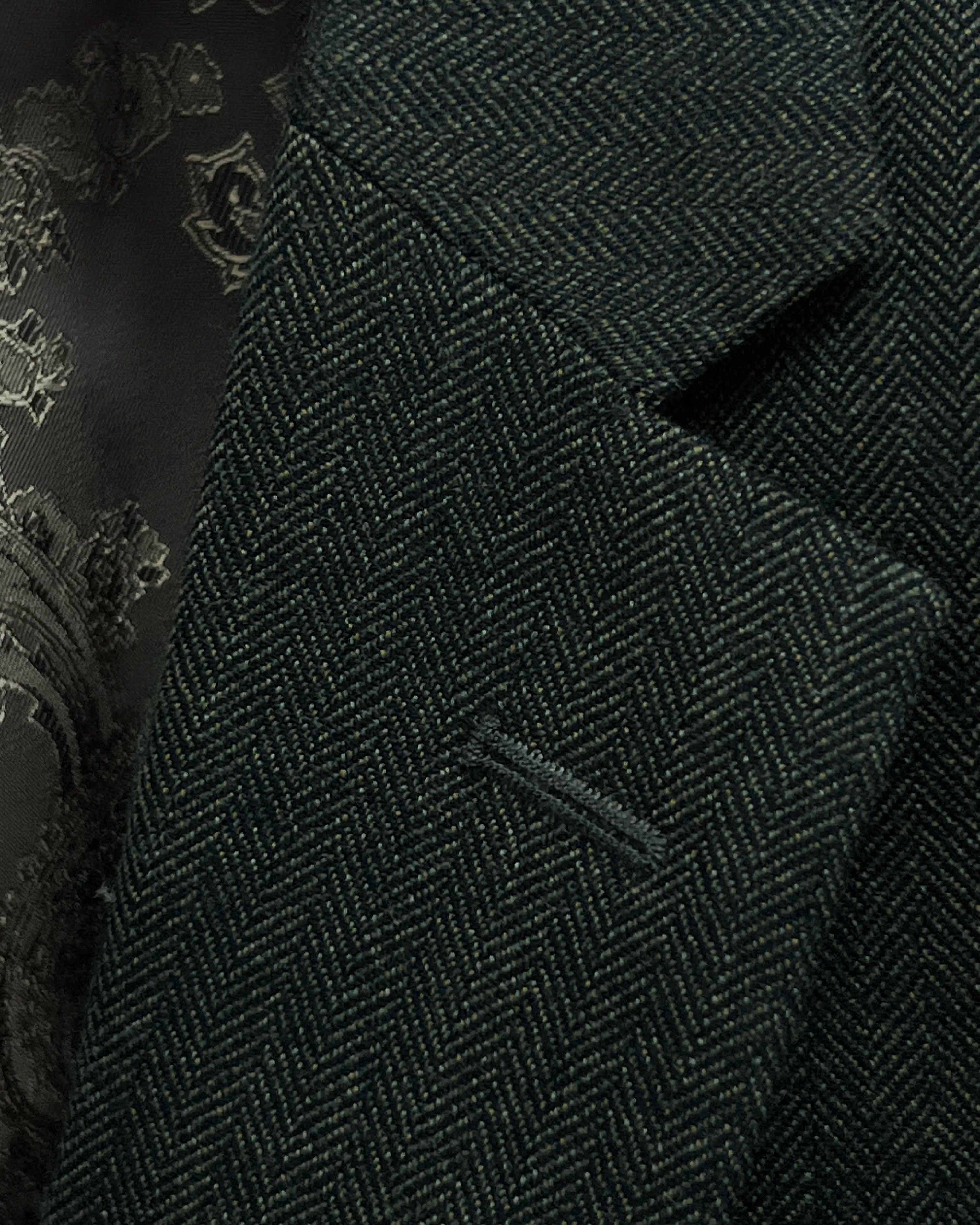 Lapel close up of dark forest green herringbone men's suit showing standard lapel buttonhole