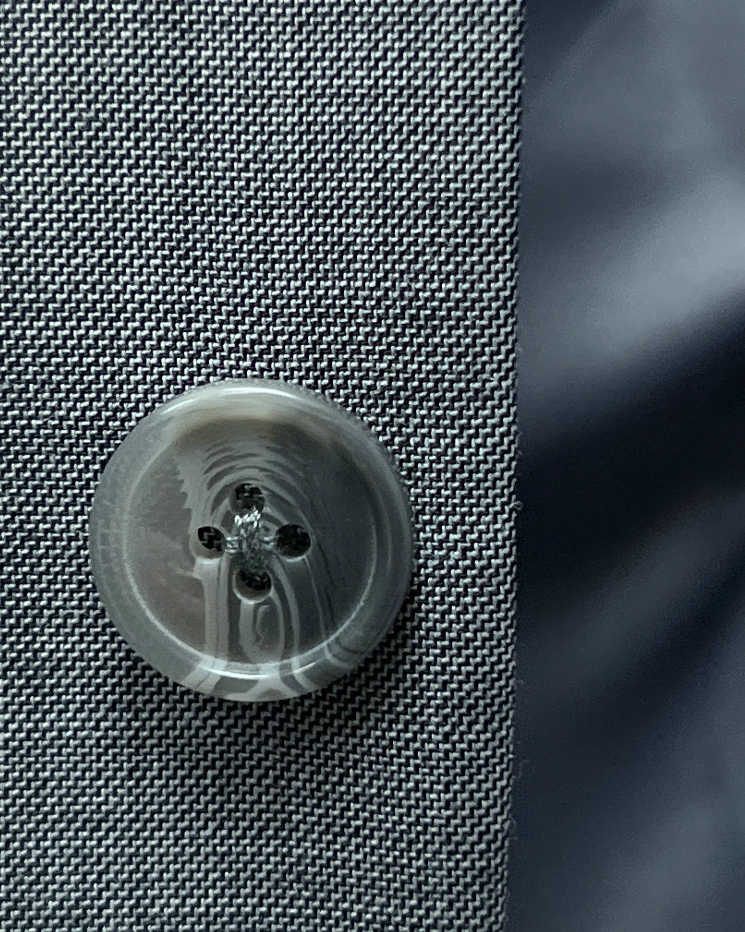 Button close up of grey sharkskin men's suit showing grey horn buttons