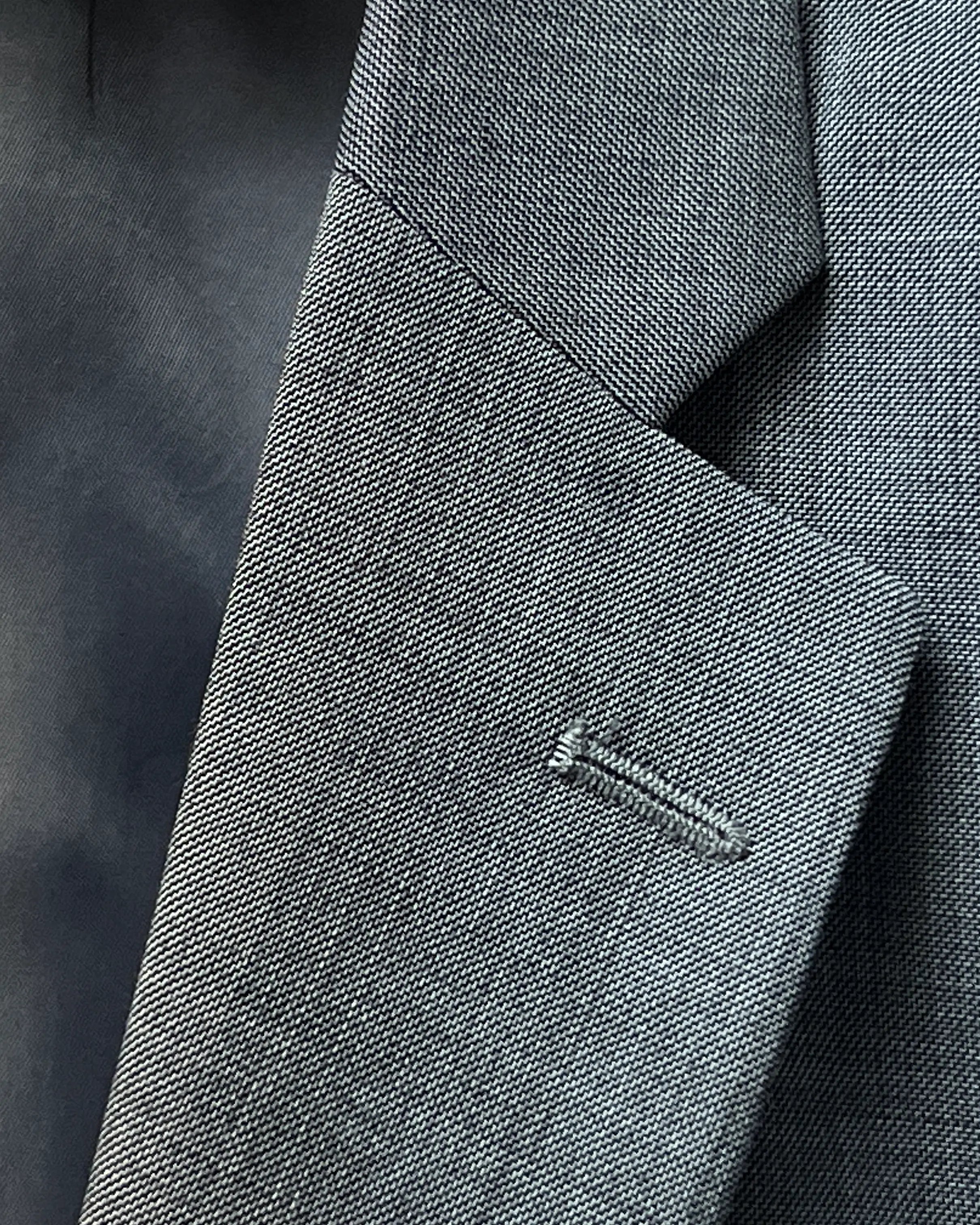 Lapel buttonhole close up of grey sharkskin men's suit showing standard lapel buttonhole stitching