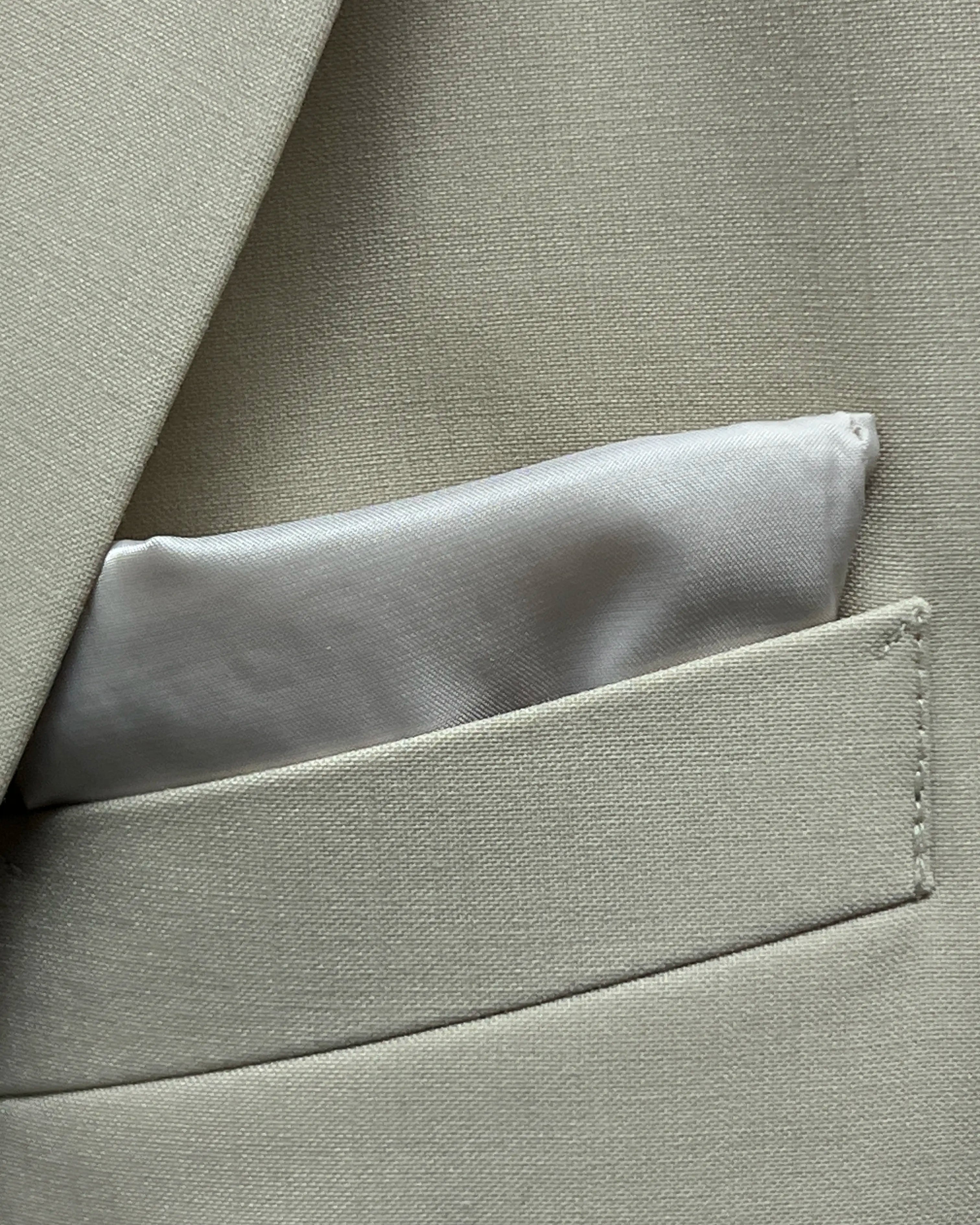 Pocket square detail of light beige plain men's suit showing built in lining pocket square