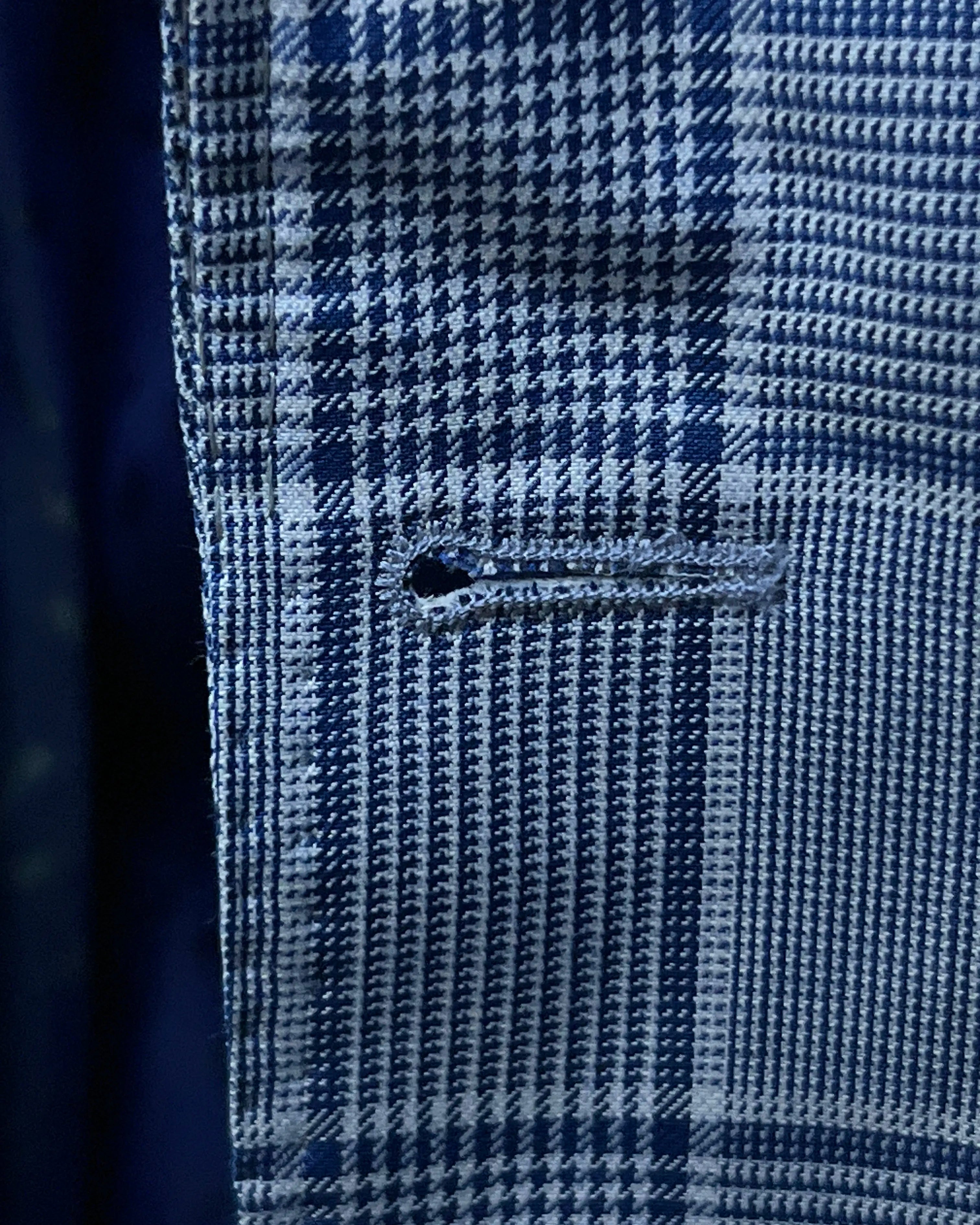 Buttonhole close up of light blue Prince of Wales glen plaid with navy windowpane men's suit showing front buttonhole detail