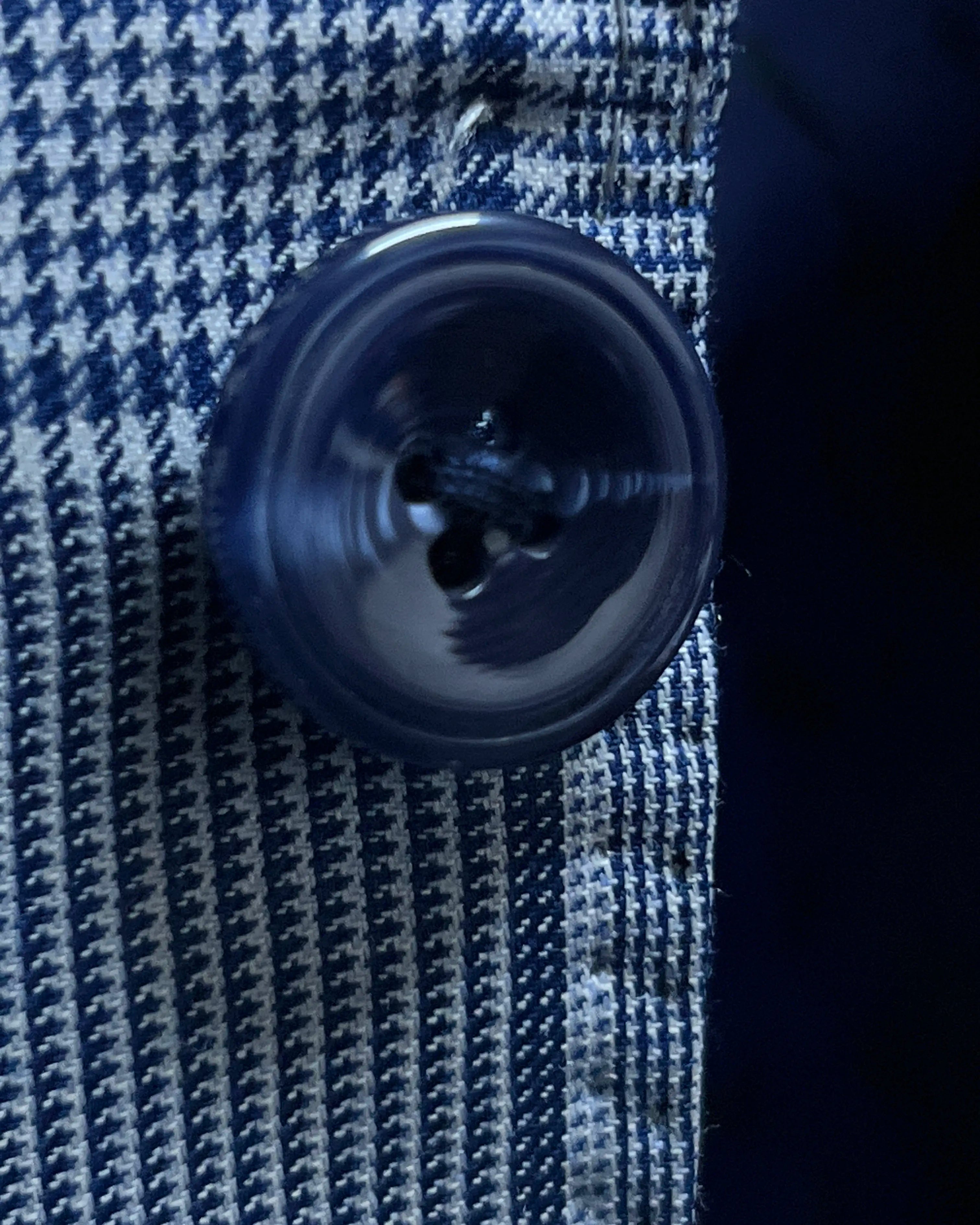 Button close up of light blue Prince of Wales glen plaid with navy windowpane men's suit showing dark navy horn buttons