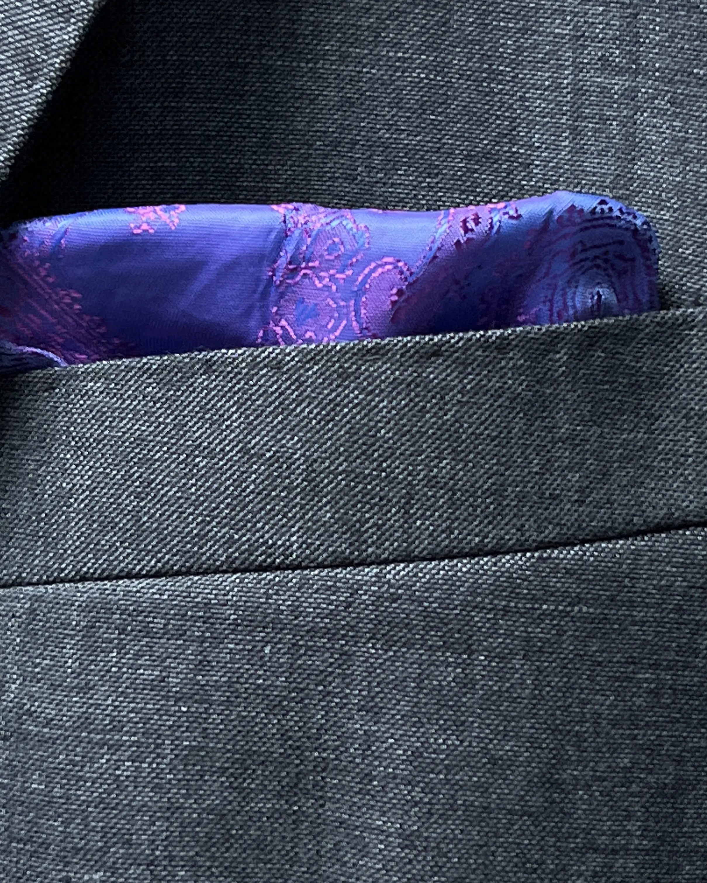Built in lining pocket square detail of medium grey sharkskin men's suit showing purple paisley lining used as pocket square