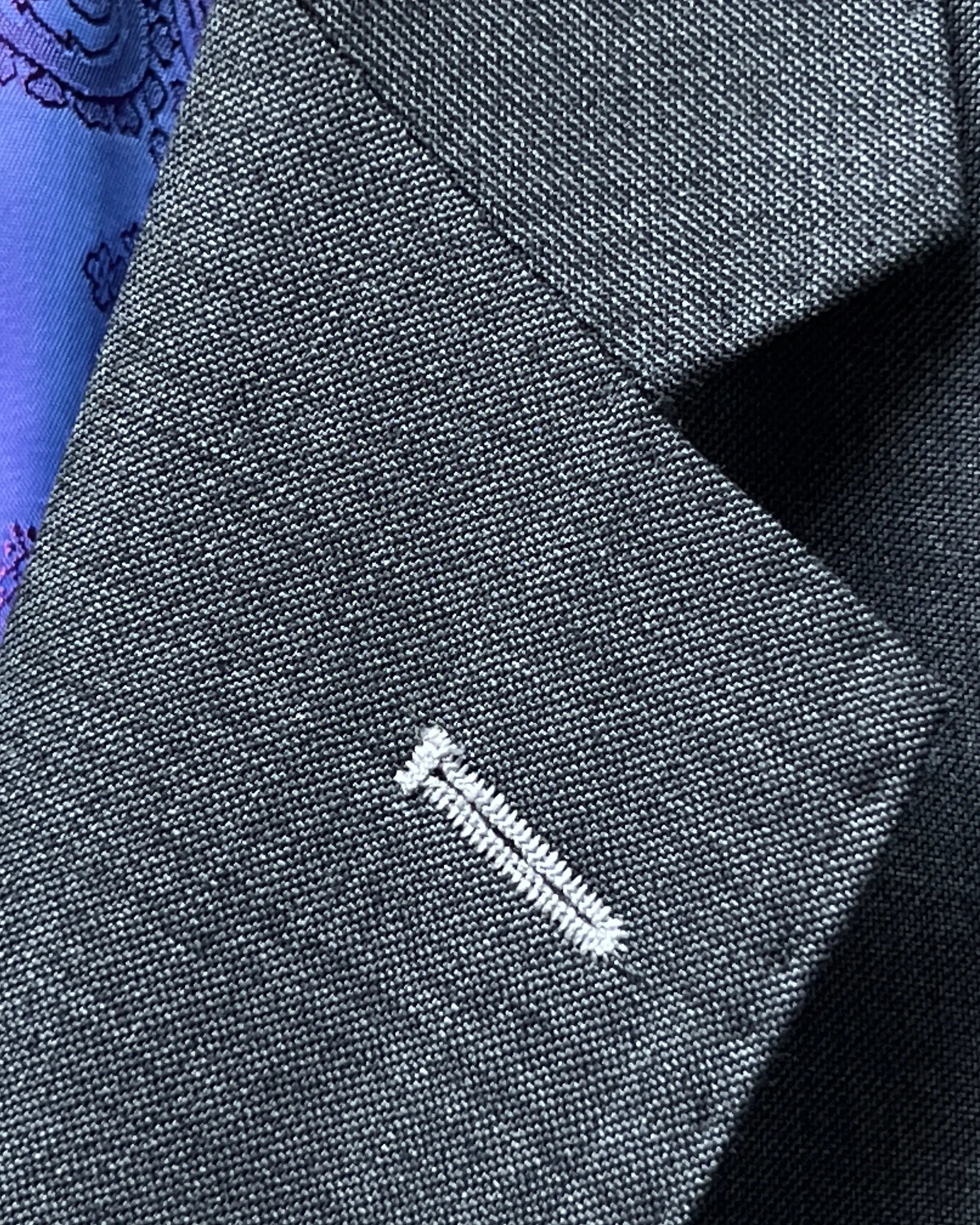 Lapel buttonhole close up of medium grey sharkskin men's suit showing white contrast lapel buttonhole stitching