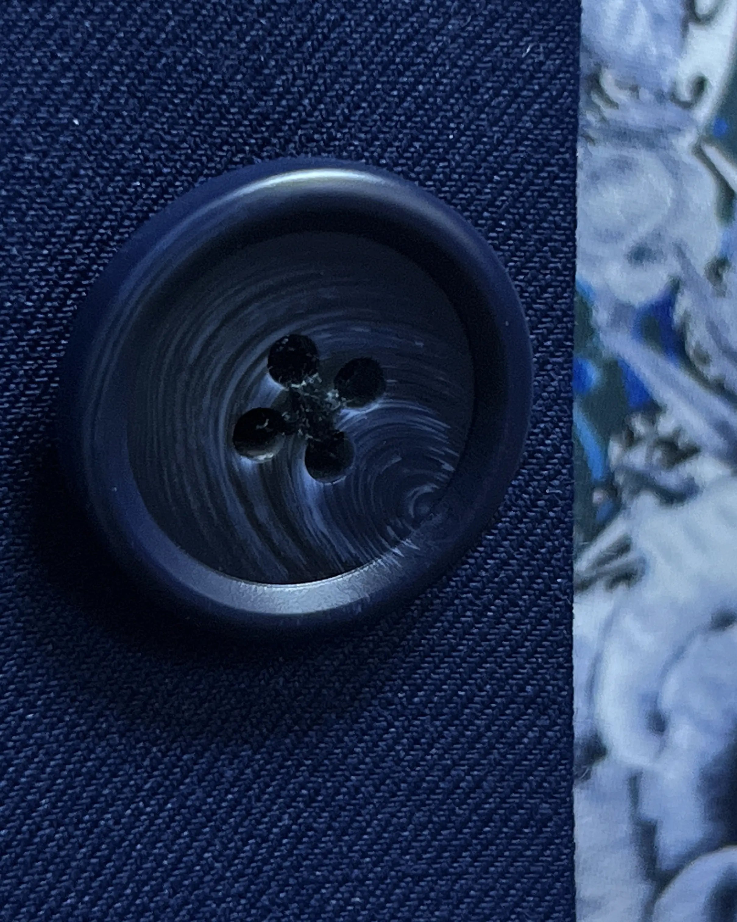 Button macro of royal blue sharkskin men's suit showing dark navy horn button material and finish.