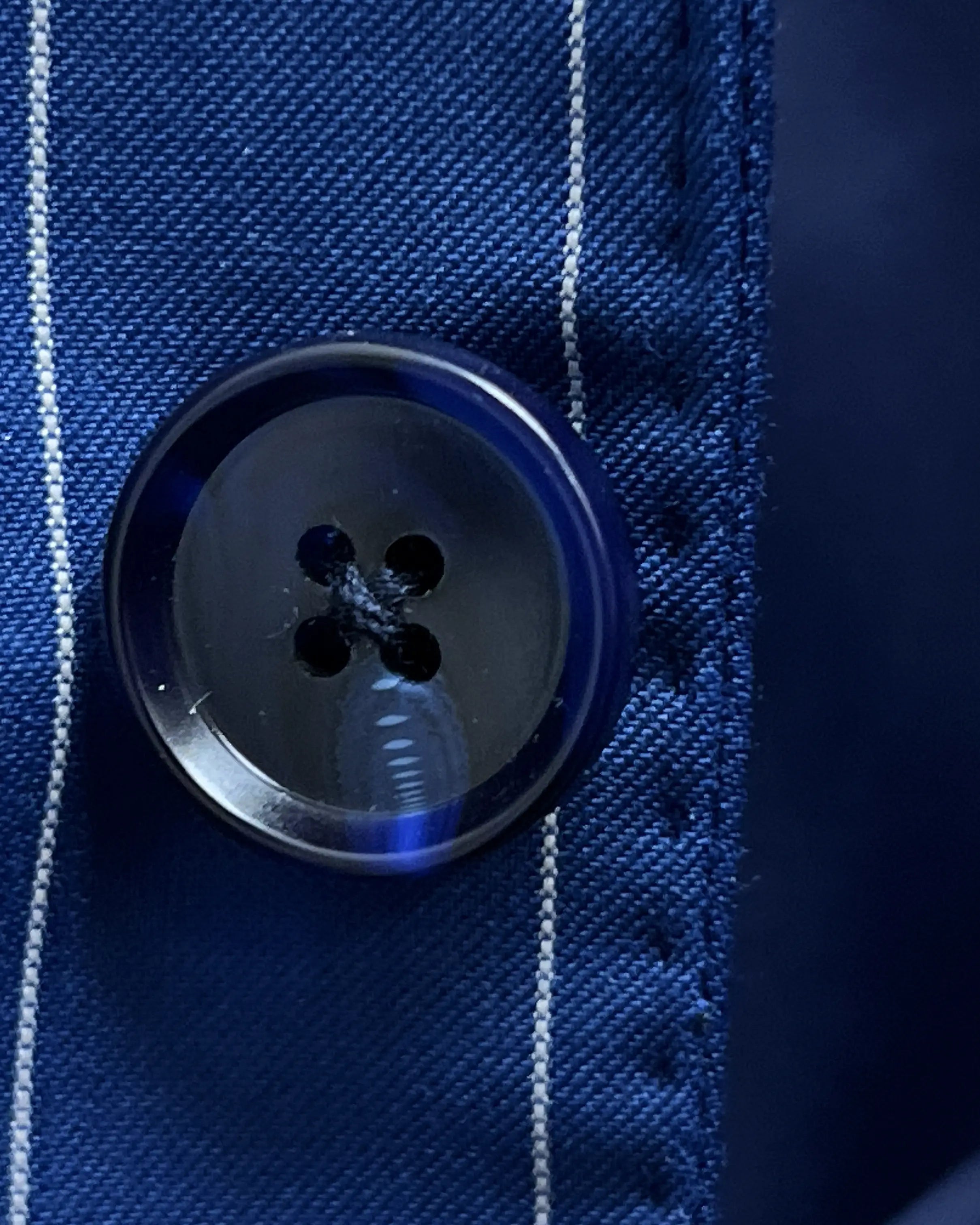 Button close up of royal blue white pinstripes men's suit showing dark navy horn buttons